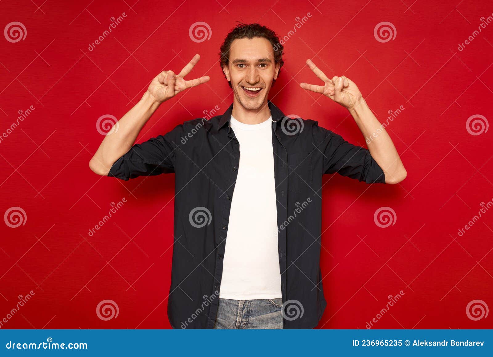 portrait of attractive smiling, childishly mature man dressed in blue shirt with smiling v-d signs highlighted in