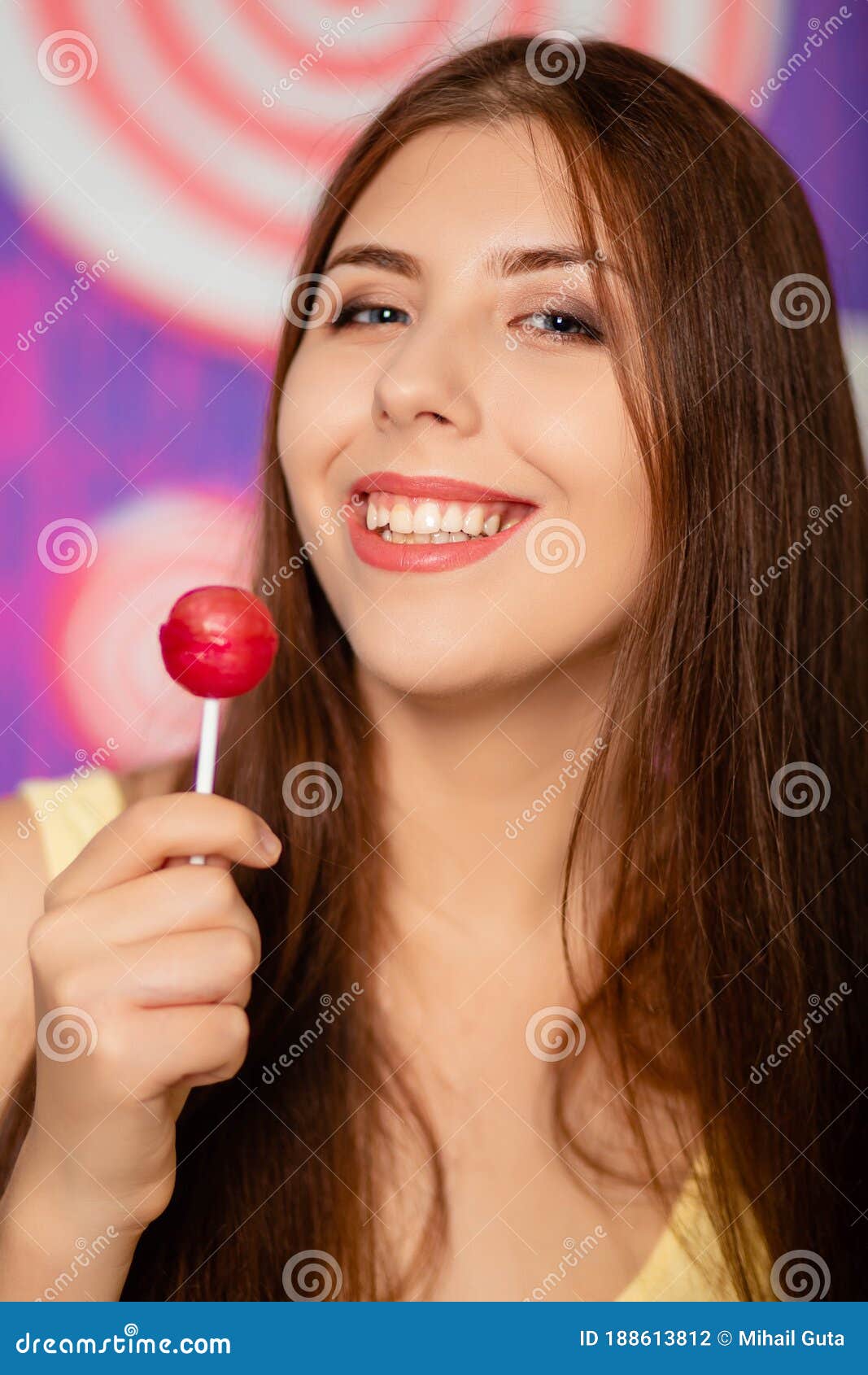 Portrait Of An Attractive Woman With A Lollipop In Her Hands On A Background Of Abstract Wall