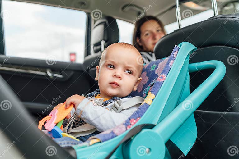 Portrait of Baby in Car Seat while Mother Driving a Passenger Car. Scene Captures Moment of Care