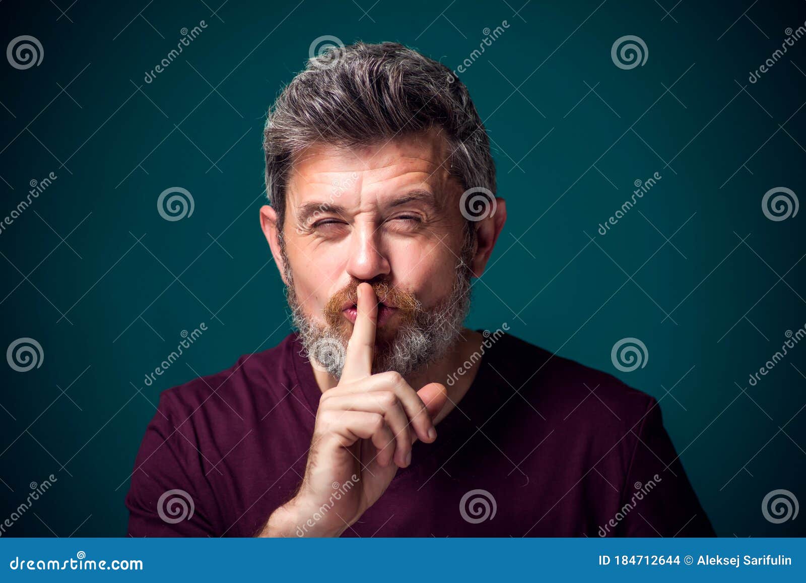 a portrait of bearded man showing hush gesture. people and emotions concept