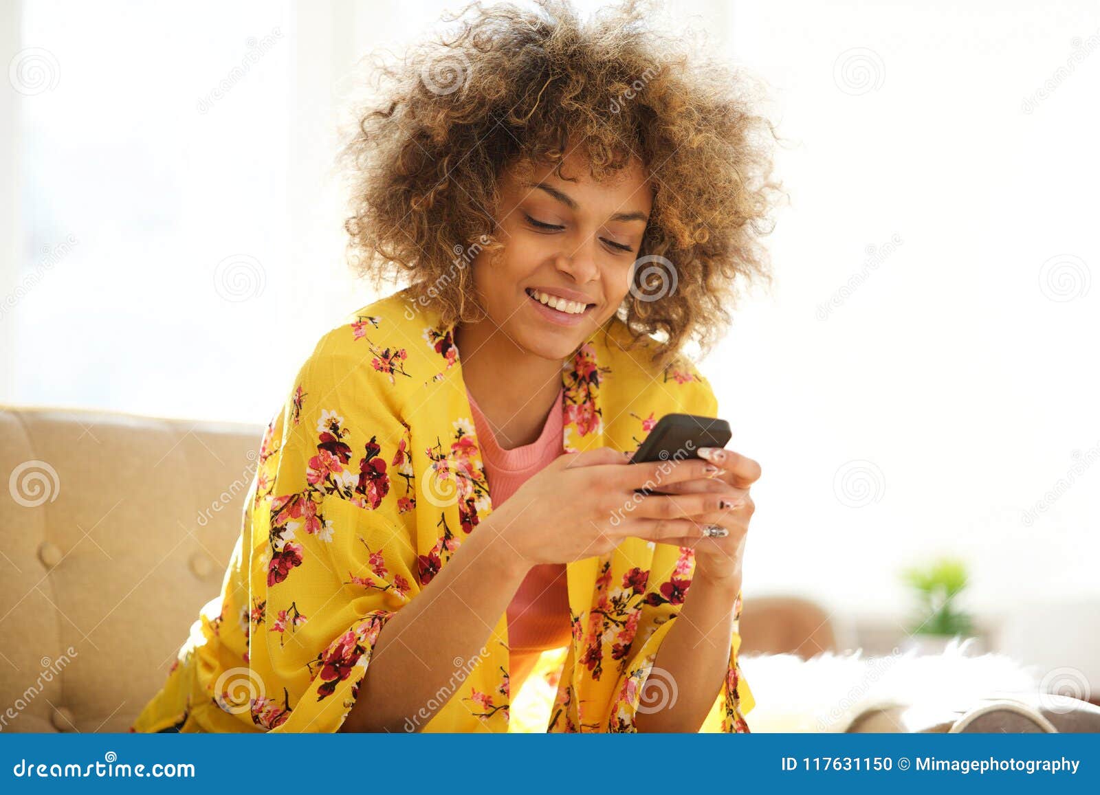beautiful african american woman using cellphone at home
