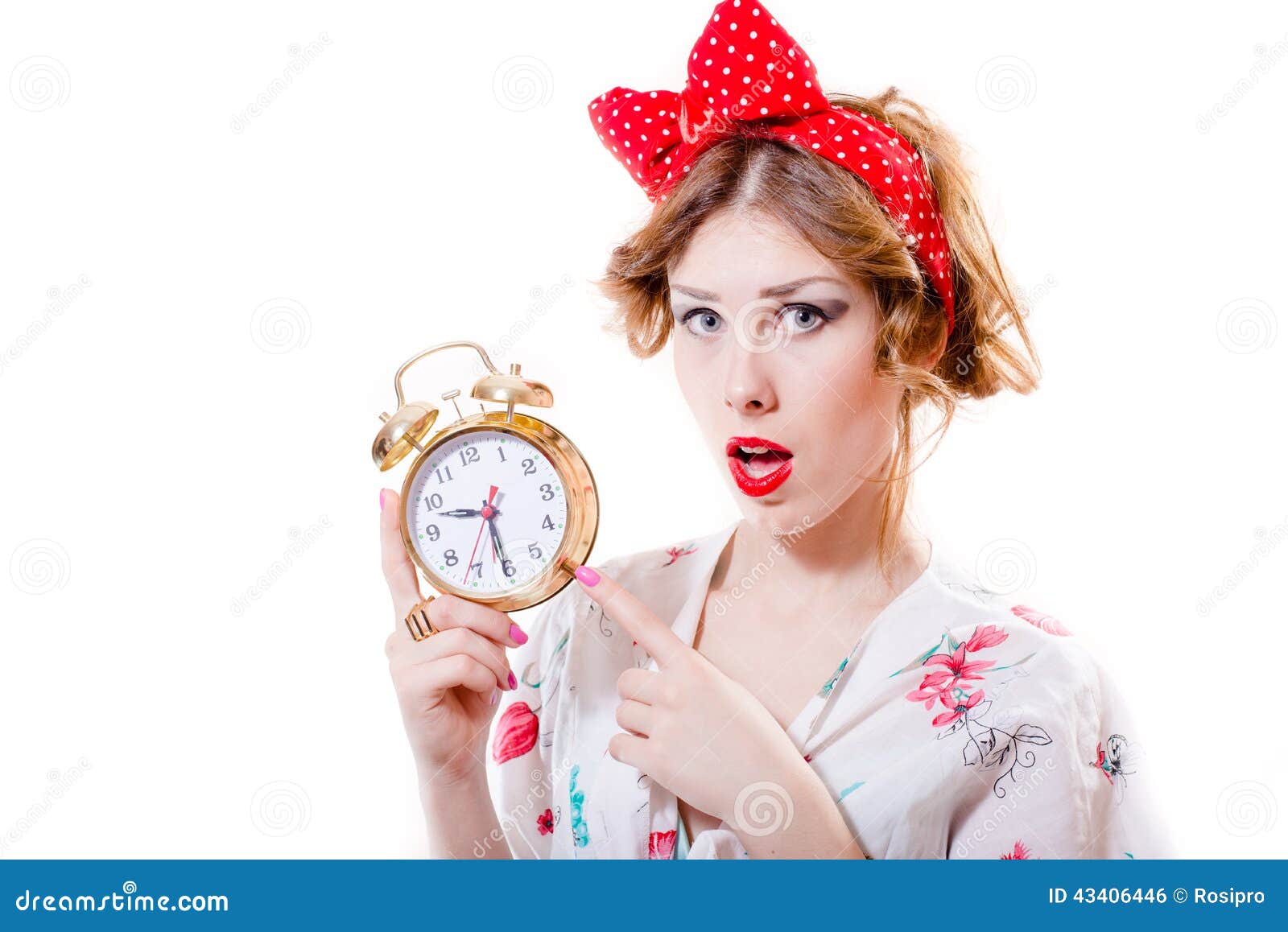 portrait of beautiful blond pinup girl showing at 9.30 on alarm clock & looking at camera surprised on white background