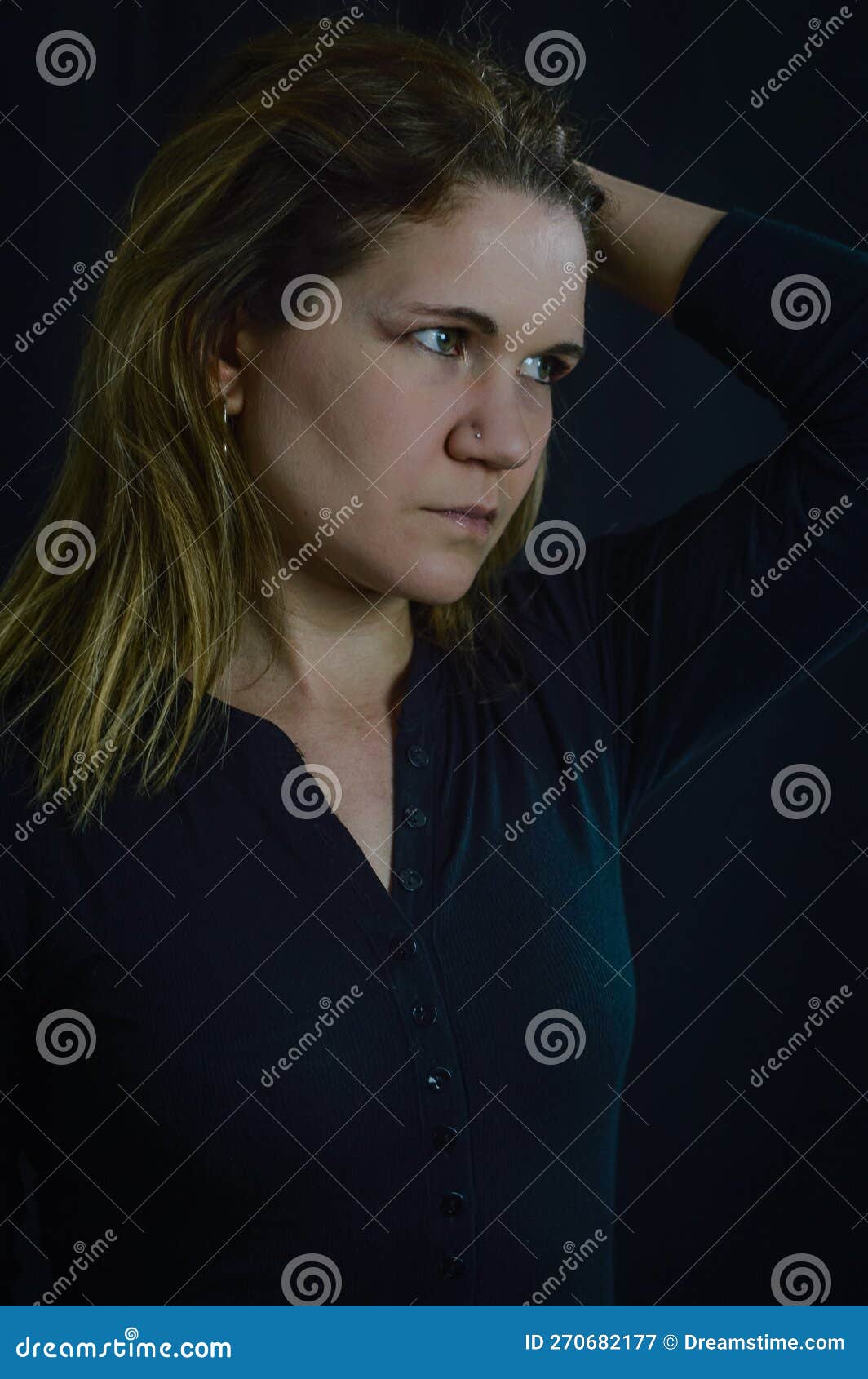 portrait of a beautiful blonde woman who holds her hair with one hand and looks longingly into the distance