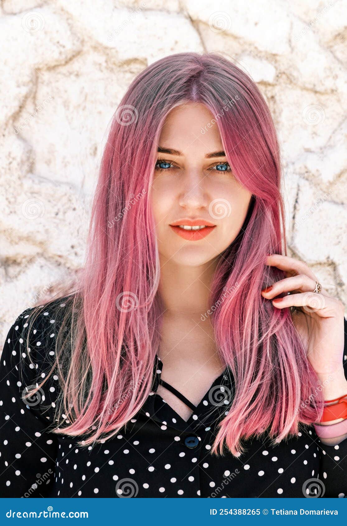 Portrait Of A Beautiful Blue Eyed Woman With Pink Hair Looking Into The Camera Against A Light 