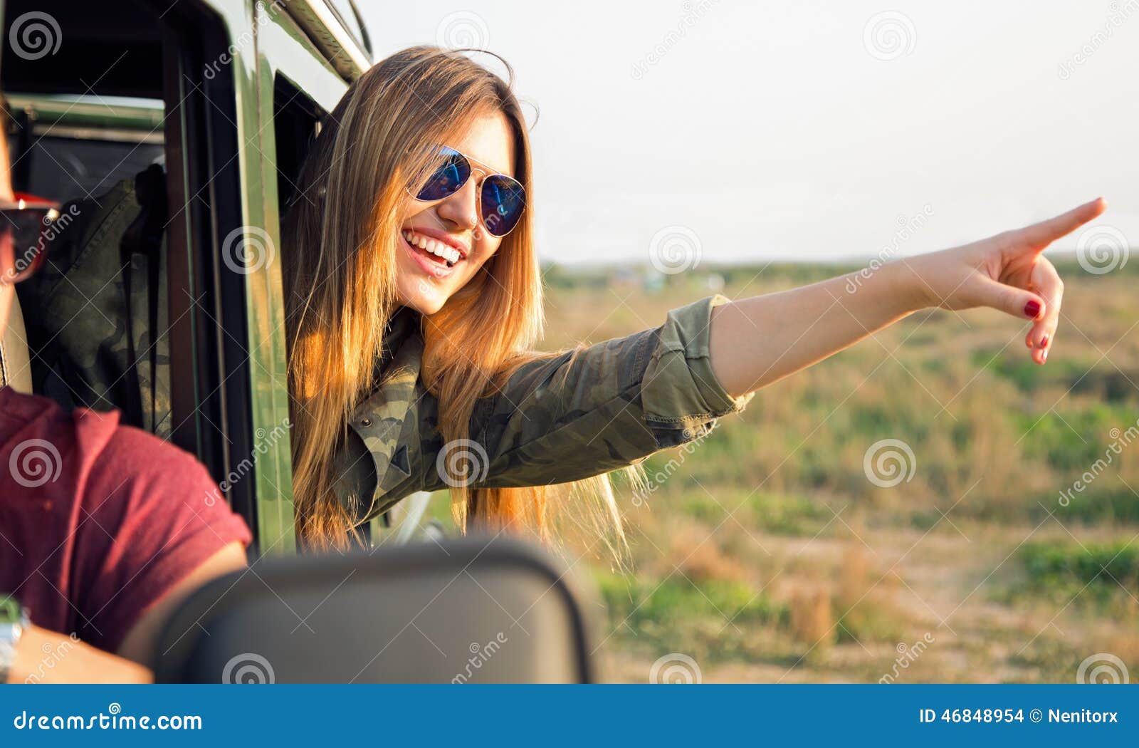 portrait of beautiful girl on car roadtrip pointing forward.