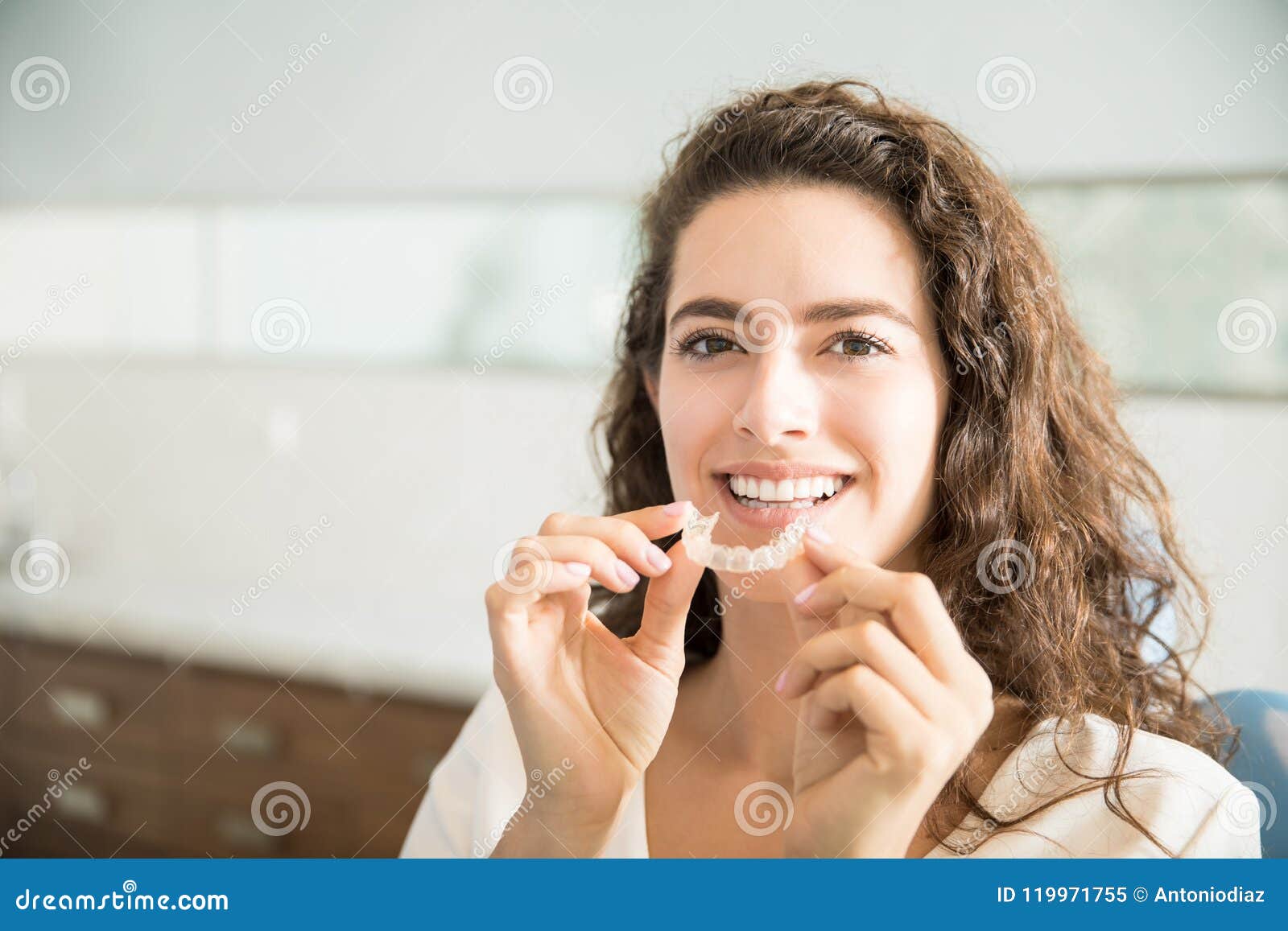 beautiful patient holding orthodontic retainers in dental clinic