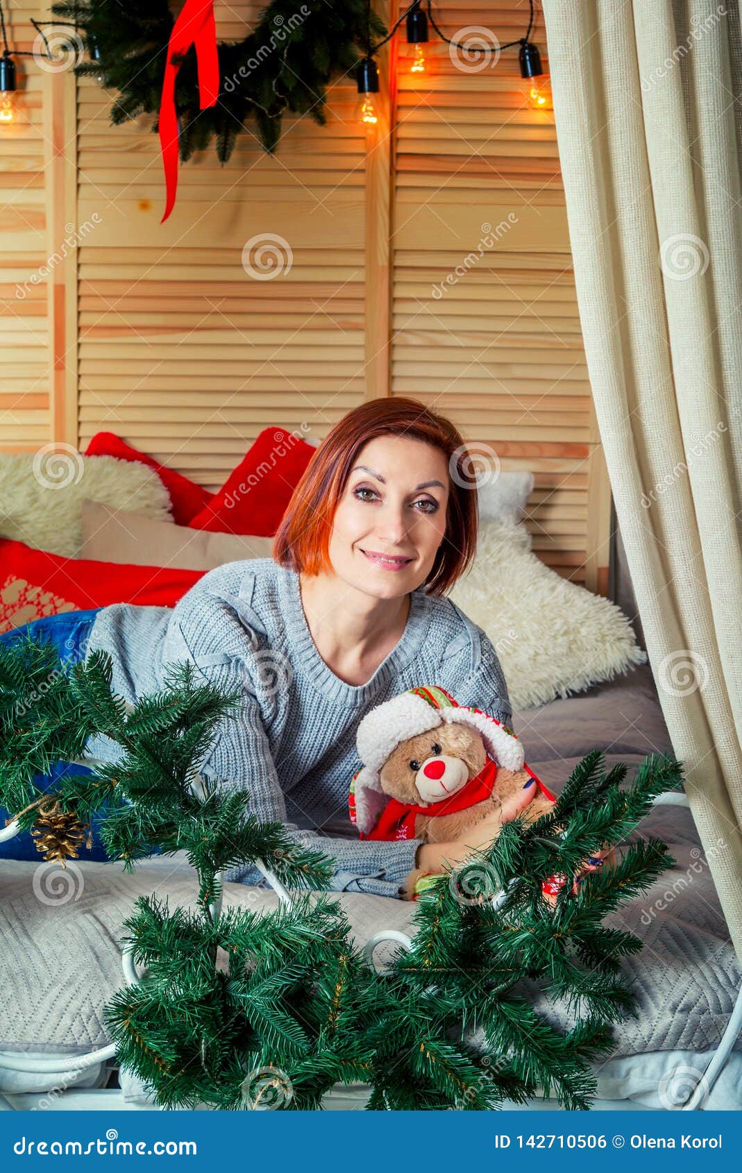 Portrait Of Beautiful Smiling Woman Laying In A Bedroom With Christmas Lights And Decorations
