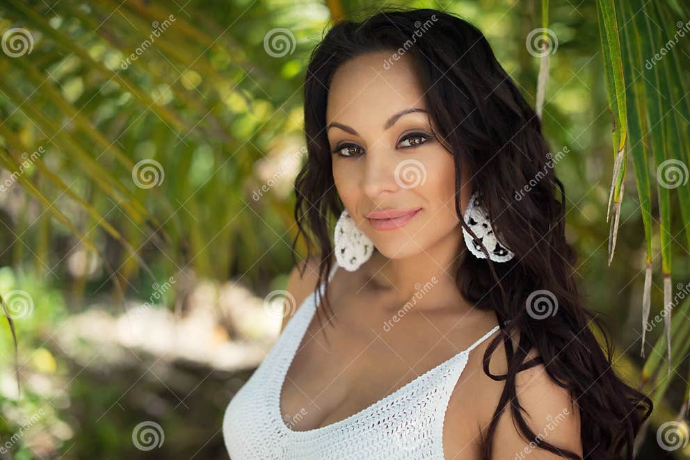 Portrait Of Beautiful Tanned Brunette Girl With Curly Hair Against A Background Of Tropical Palm