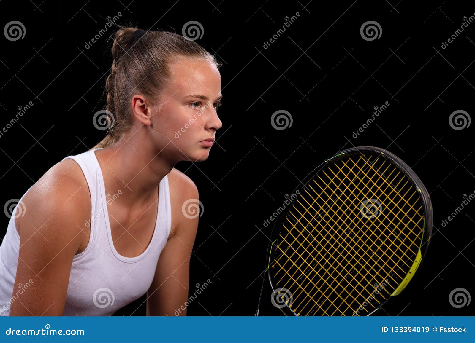 portrait of beautiful woman playing tennis indoor.  on black.