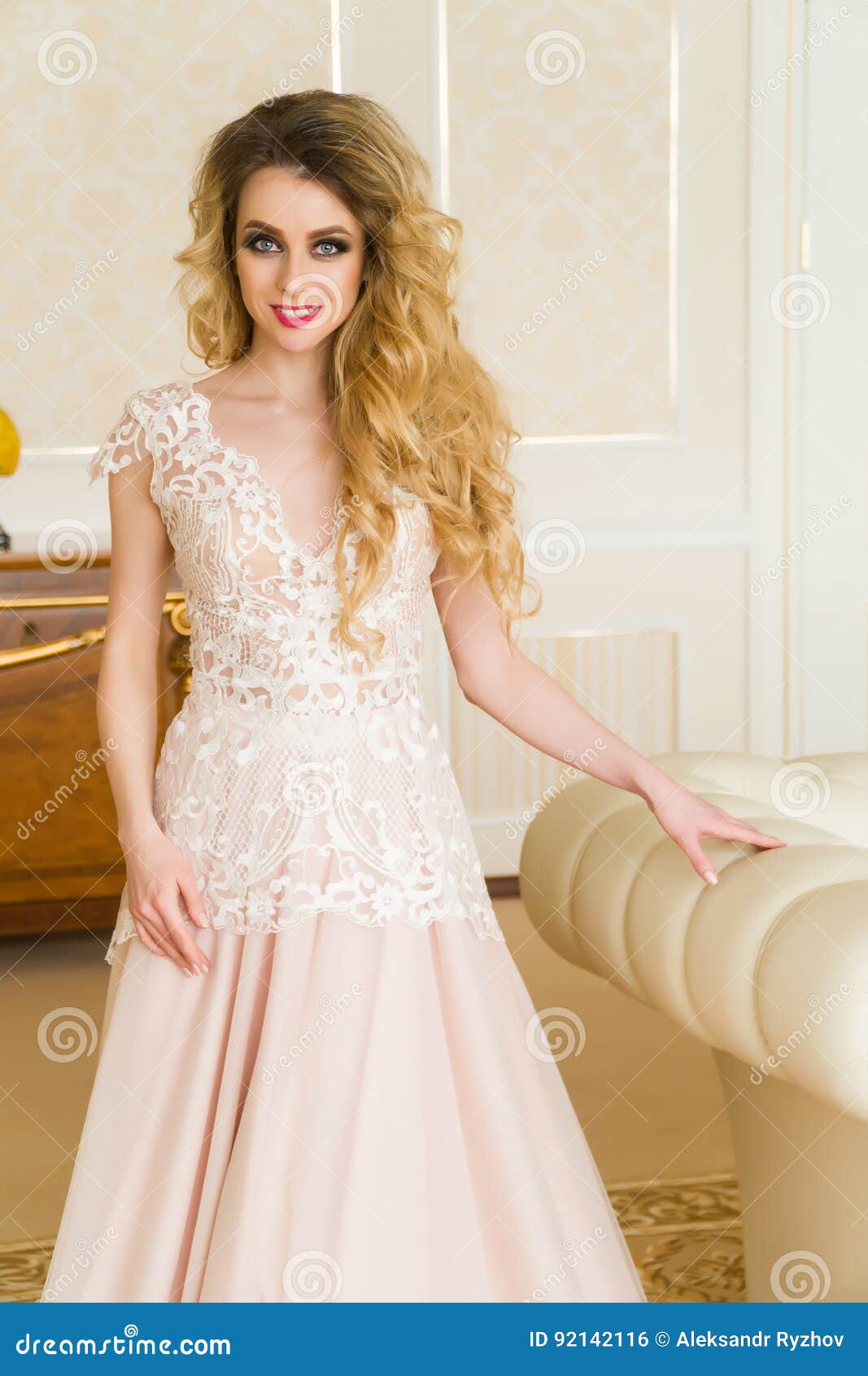 Portrait of beautiful young bride. A girl is posing in a hotel room. The lady is spinning in her wedding dress.