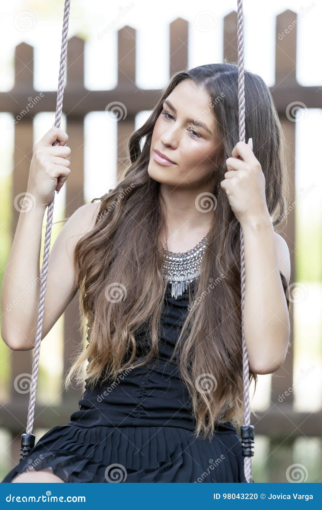 Two Hispanic American Girls Sharing Tree Swing High-Res Stock