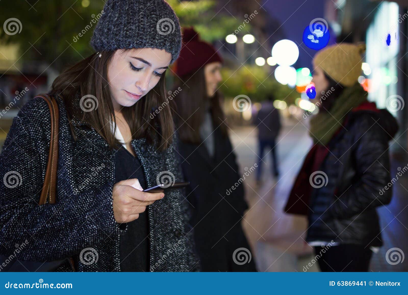 portrait of beautiful young woman using her mobile phone at nigh