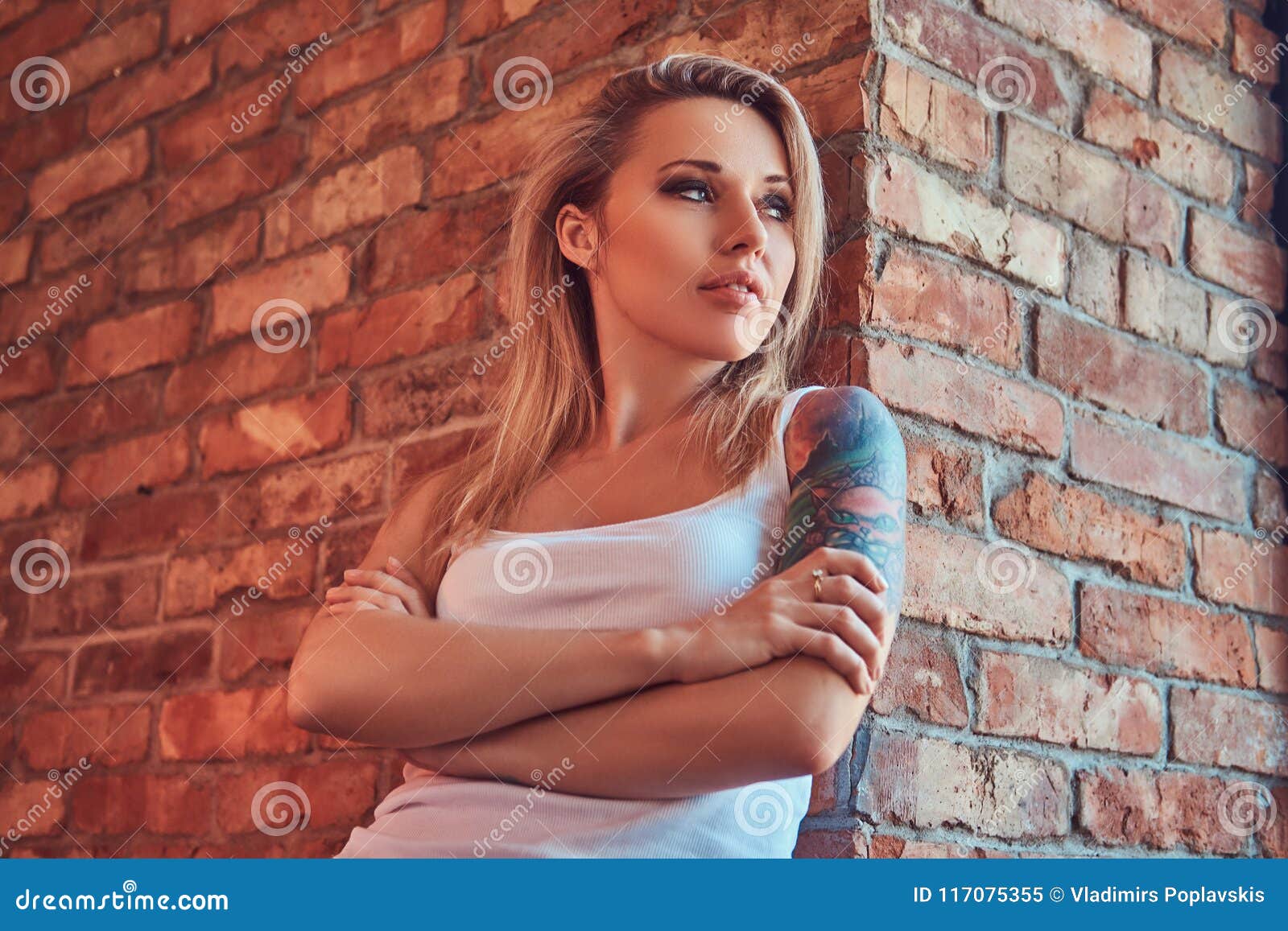 Portrait Of A Blonde Hipster Woman Standing With Crossed Arms While