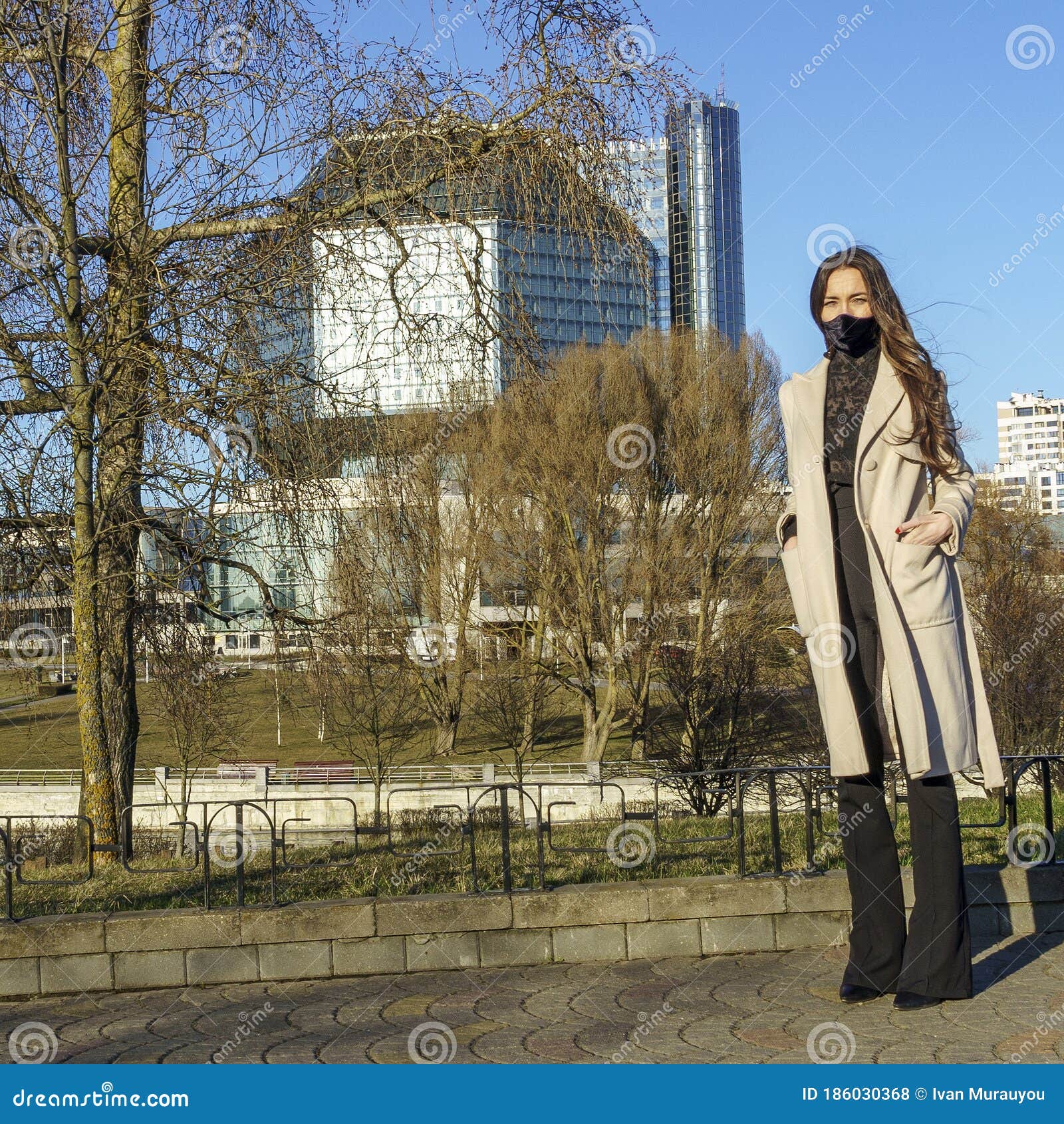 portrait of brunette woman in a protective medical mask on a cityscape background. virus protection. 2019ncov concept