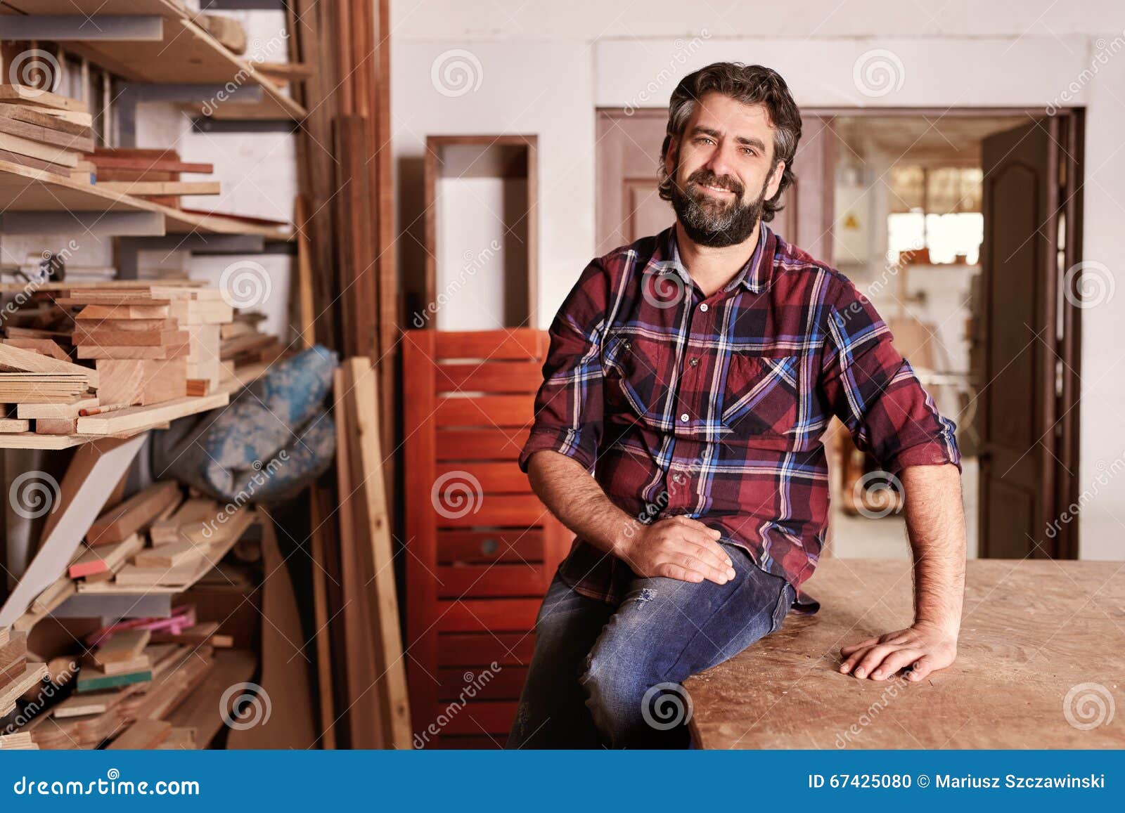 craftsman sitting in his woodwork studio for a portrait, with shelves 