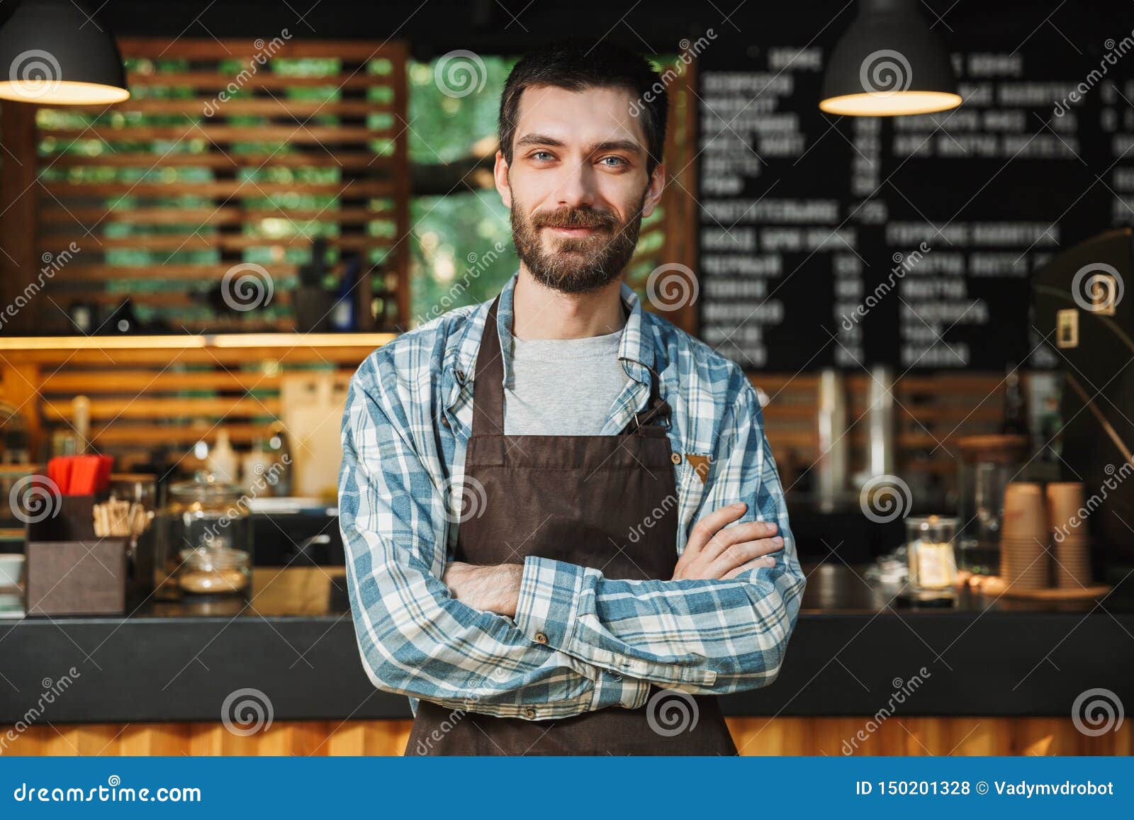 portrait of caucasian barista guy standing with arms crossed in street cafe or coffeehouse outdoor