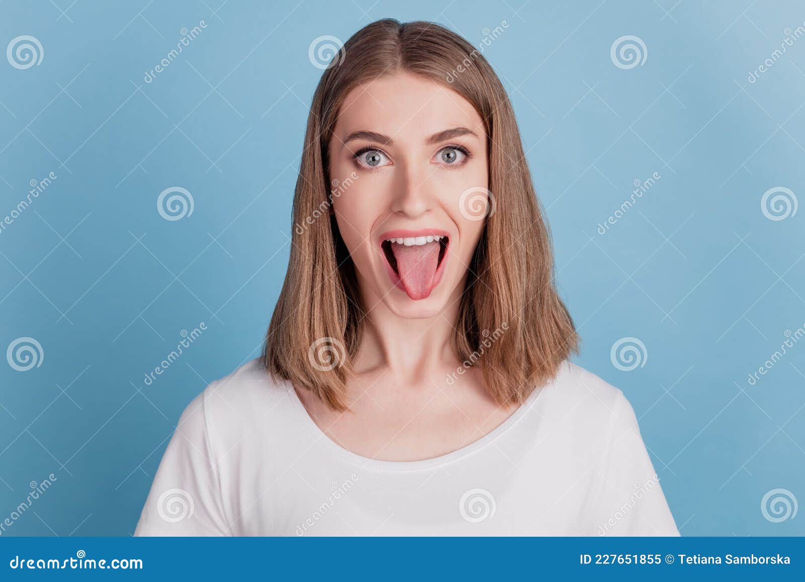 portrait of cheerful healthy girl look camera protrude tongue on blue background