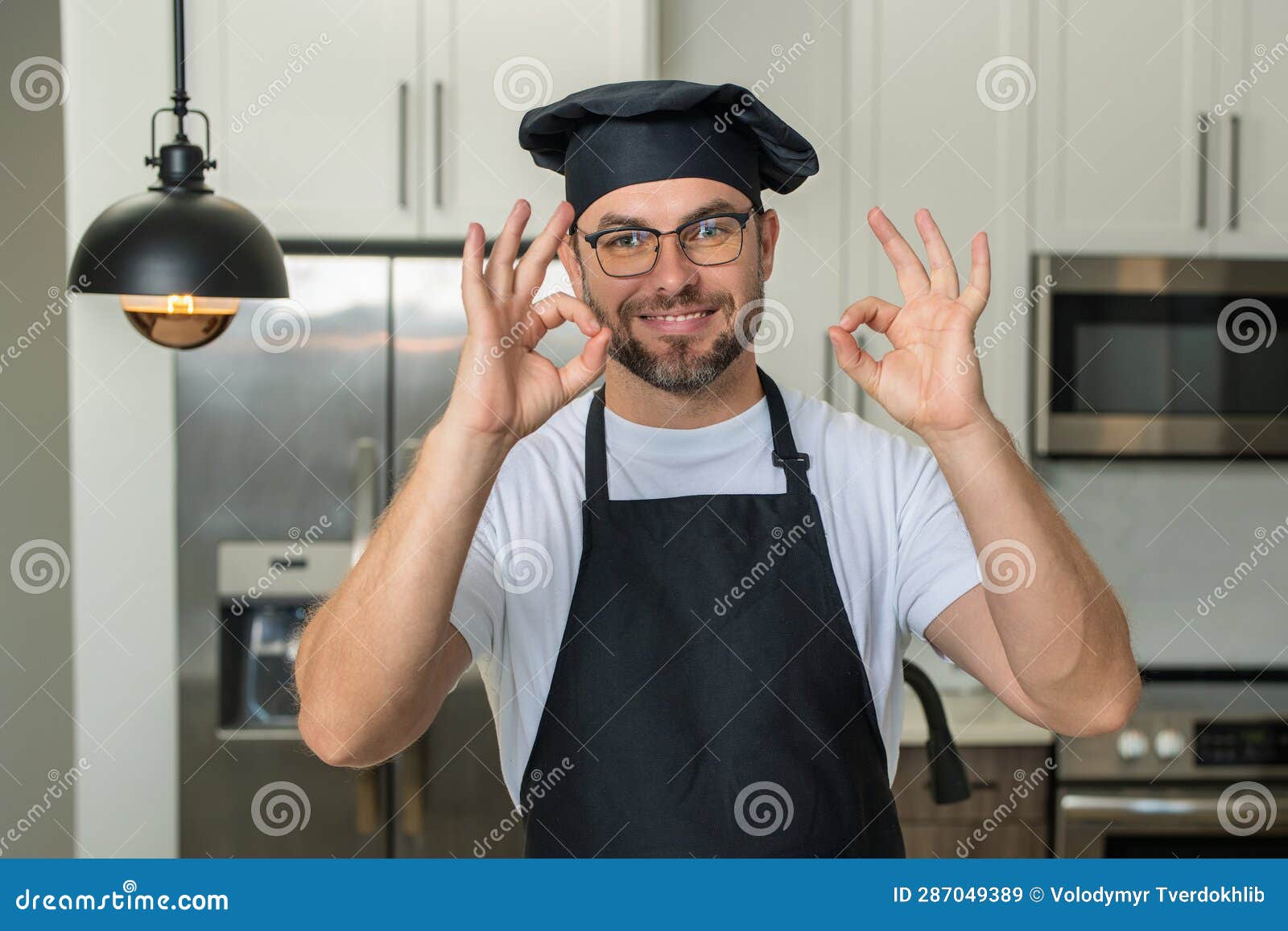 Portrait Of Chef Man In A Chef Cap In The Kitchen Man Wearing Apron portrait-of-chef-man-in-a-chef-cap-in-the-kitchen-man-wearing-apron