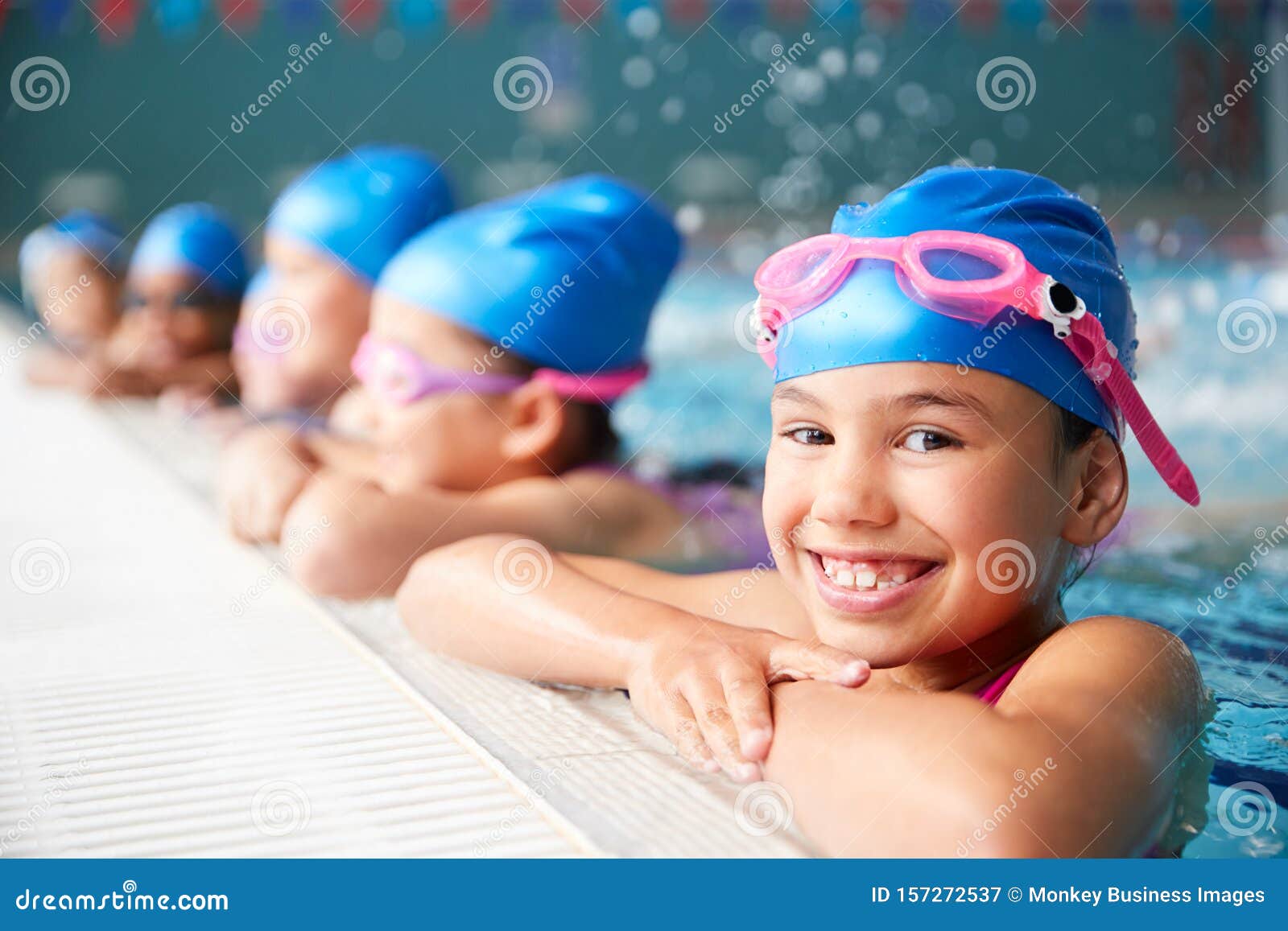 portrait of children in water at edge of pool waiting for swimming lesson