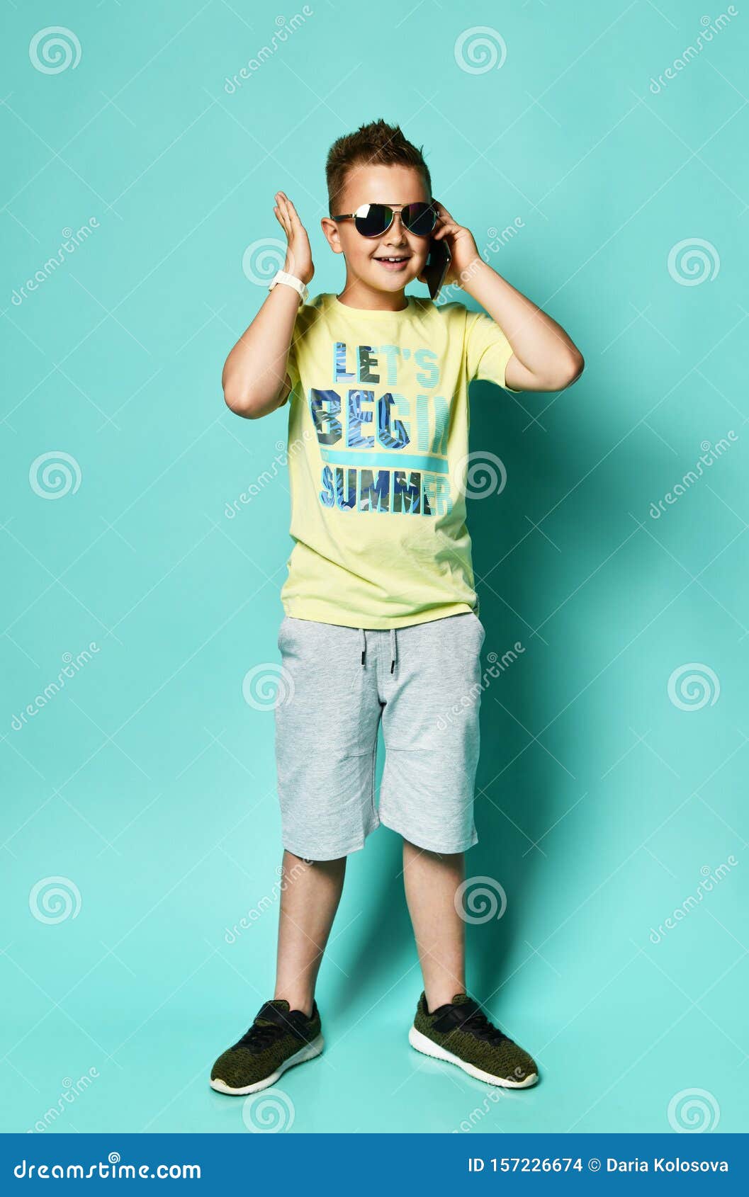 Portrait Of A Cool Young Teen Guy Talking On A Mobile Phone In Summer Style Clothes In Sunglasses On A Blue Background Stock Photo Image Of Happy Modern 157226674