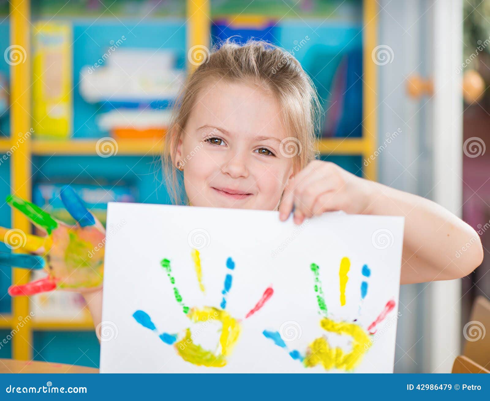 Portrait of cute little preschooler girl with colorful hands