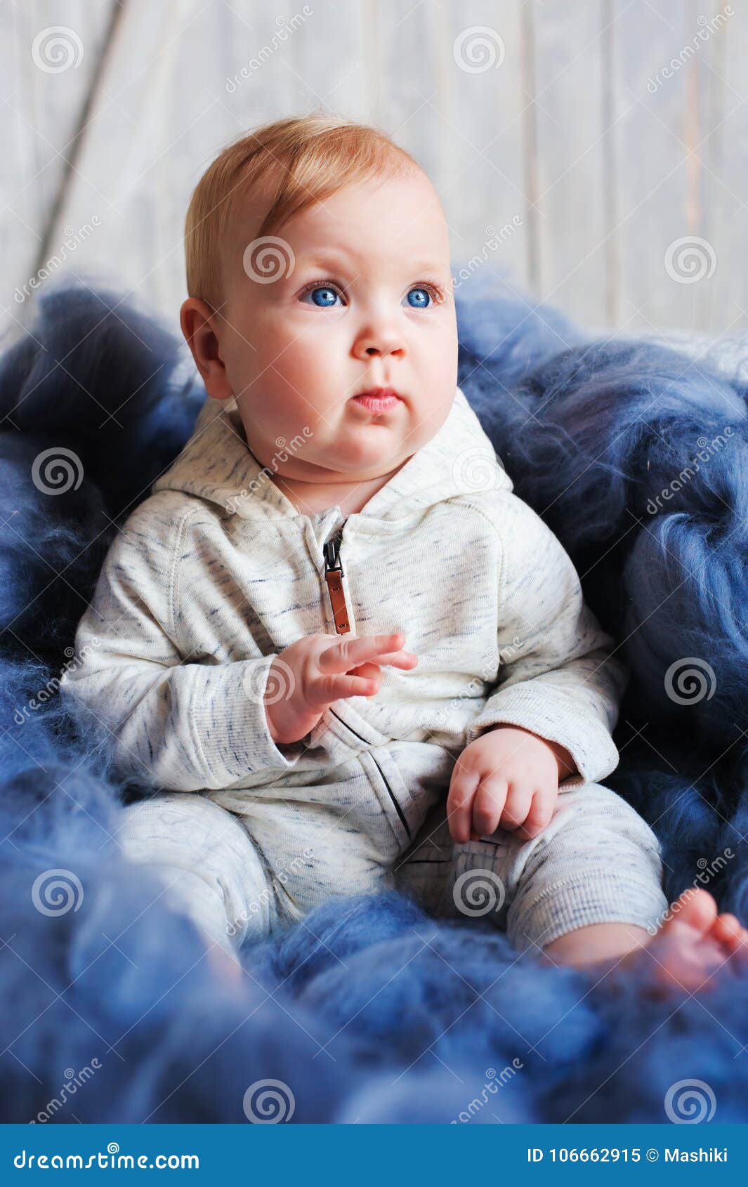 portrait of cute 8 month old baby girl sitting on the bed on oversize knitted blanket