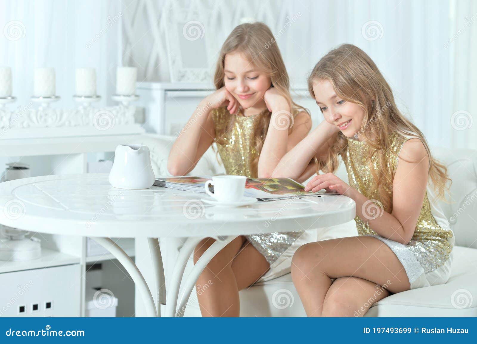 portrait of cute twin sisters with modern magazine