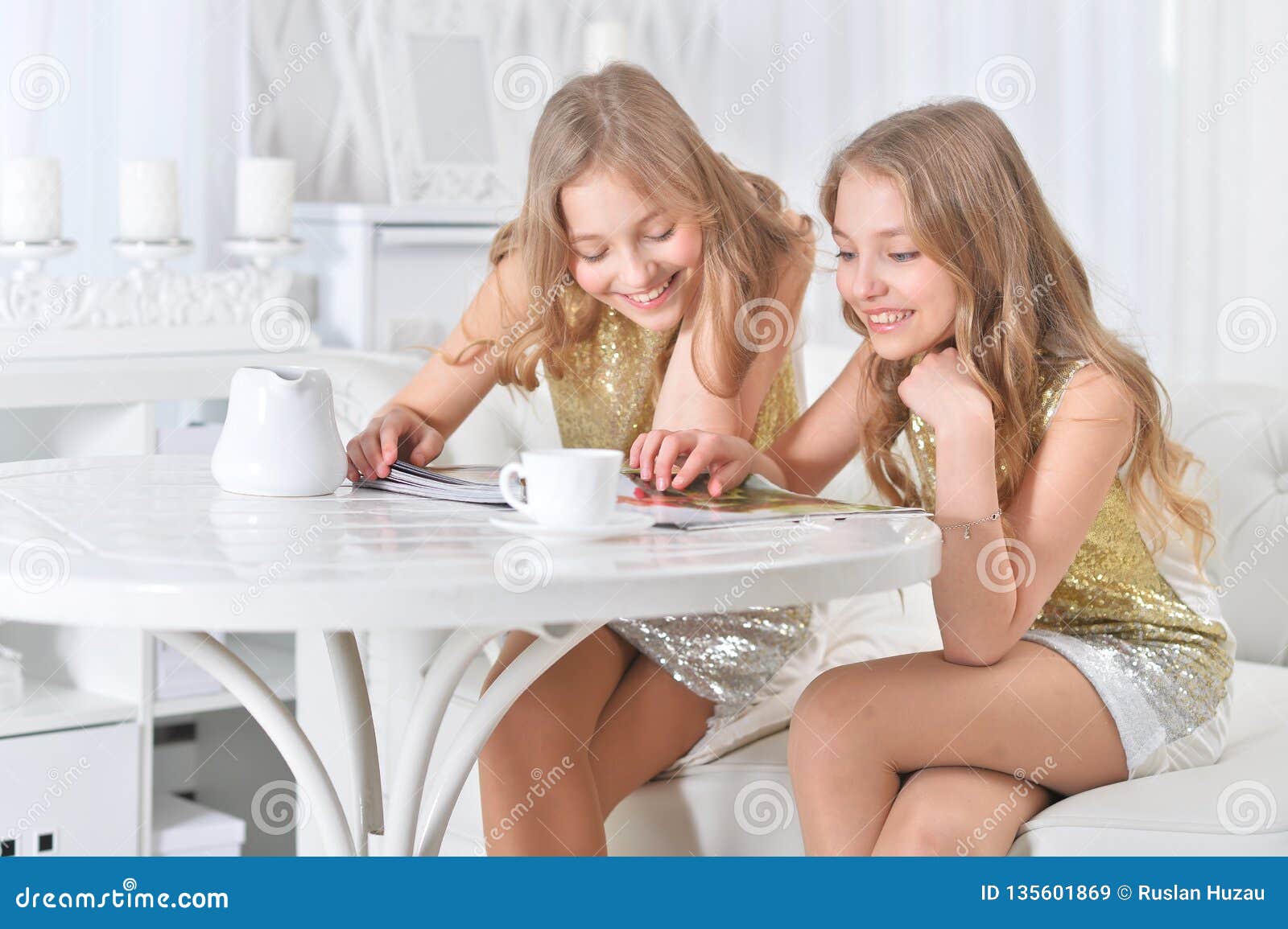 cute twin sisters sitting at kitchen table