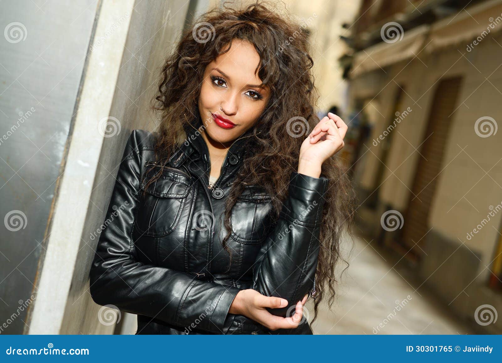 Femme De Couleur Attirante Dans Le Jacke En Cuir De Port De Fond Urbain
