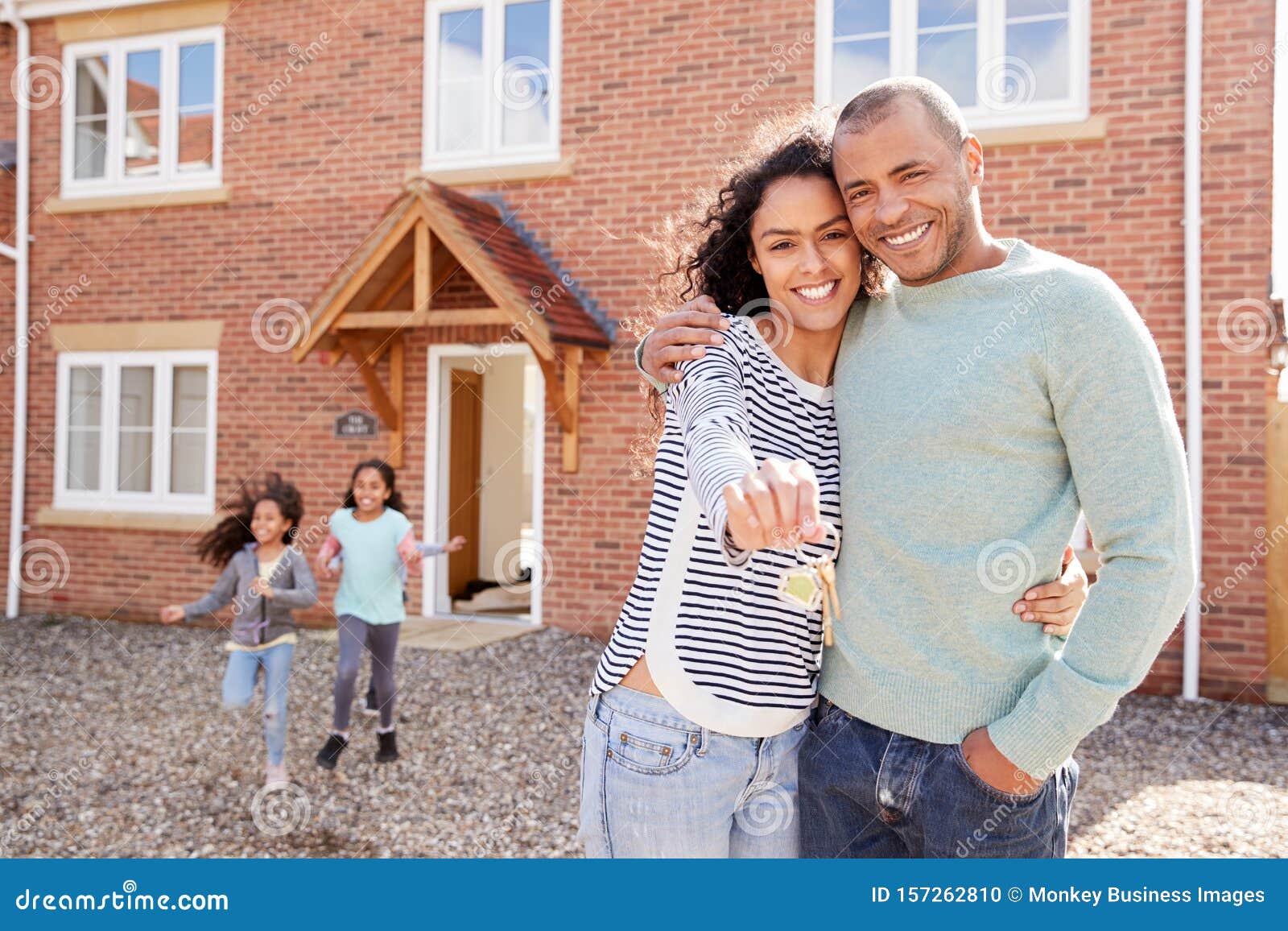 portrait of family holding keys standing outside new home on moving day