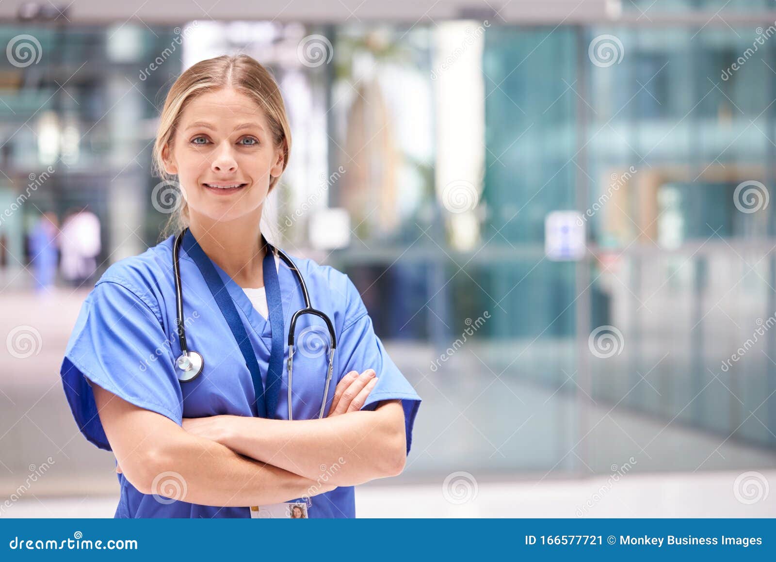 portrait of female doctor with stethoscope wearing scrubs standing in modern hospital building