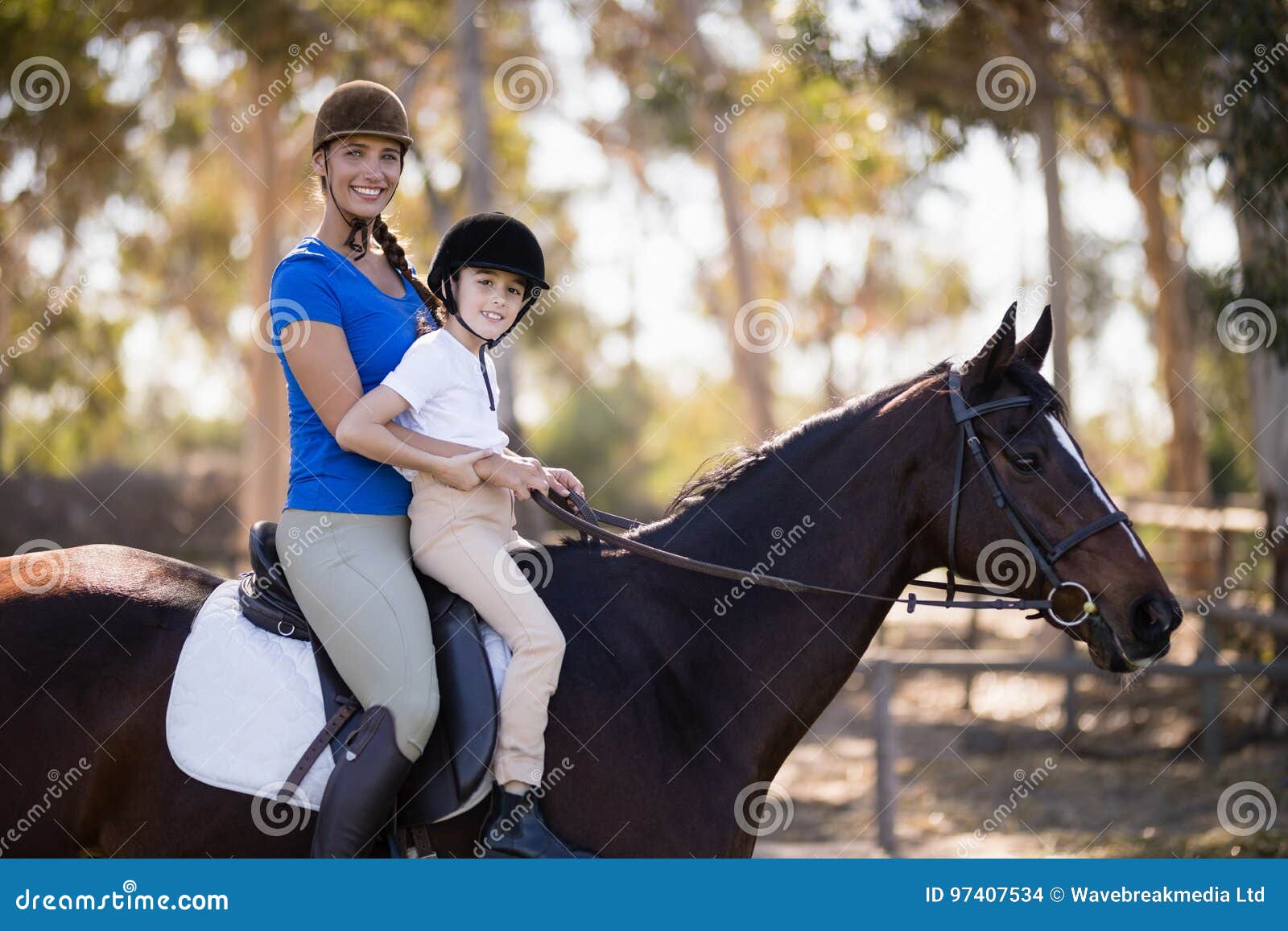 portrait of female jockey and girl sitting horseback riding
