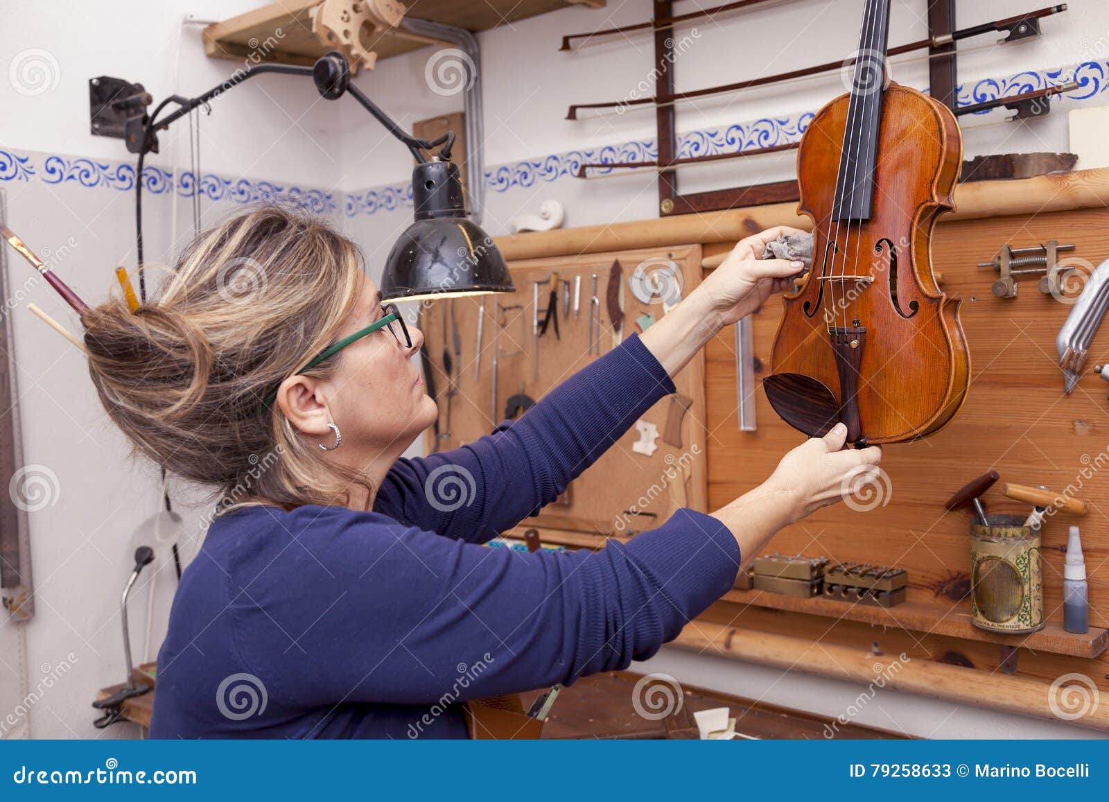 Portrait of Female Mature Violin Maker while Testing the Violins Stock