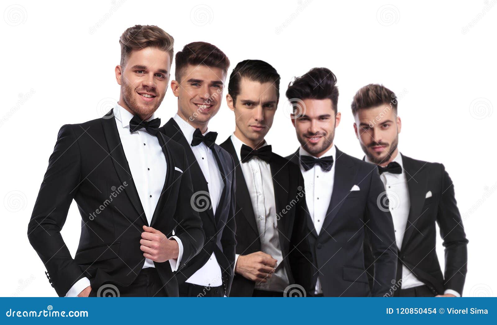 portrait of five attractive men wearing tuxedoes standing in lin