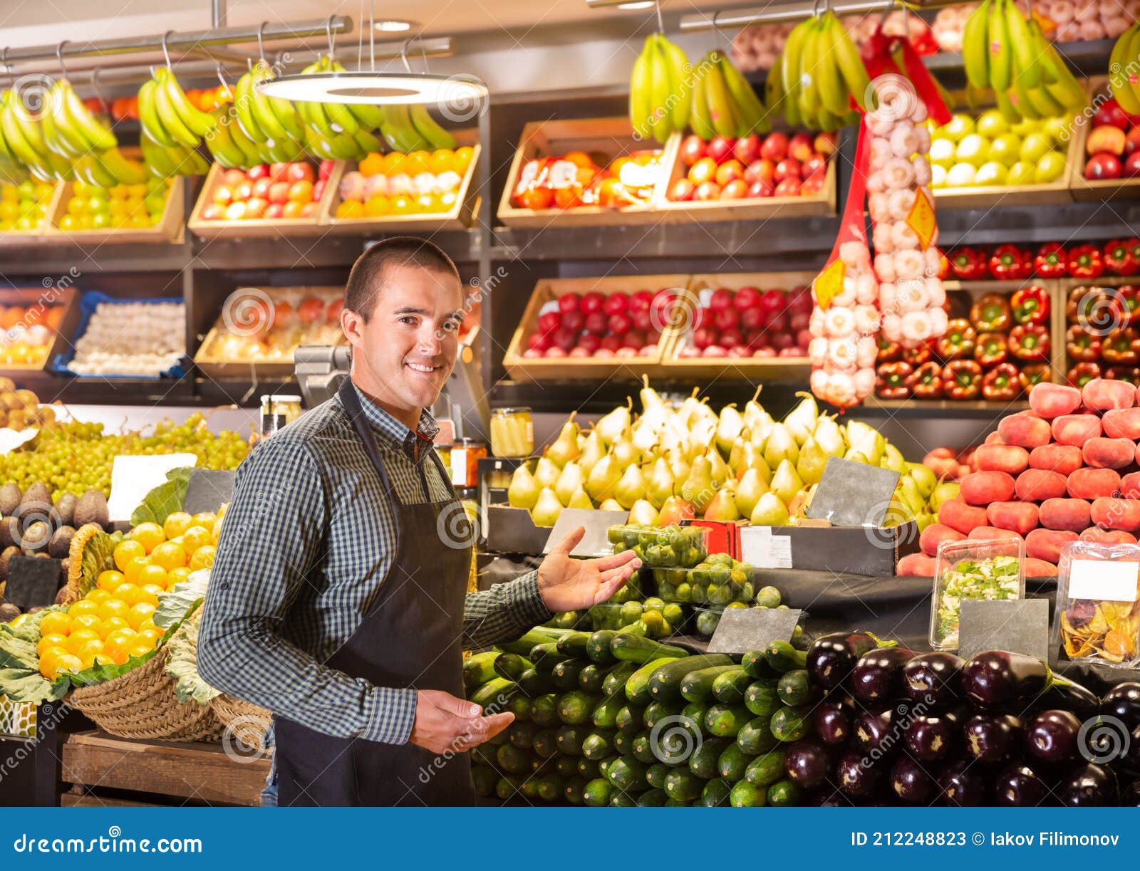 male shop assistant standing of counter of vegetable shop