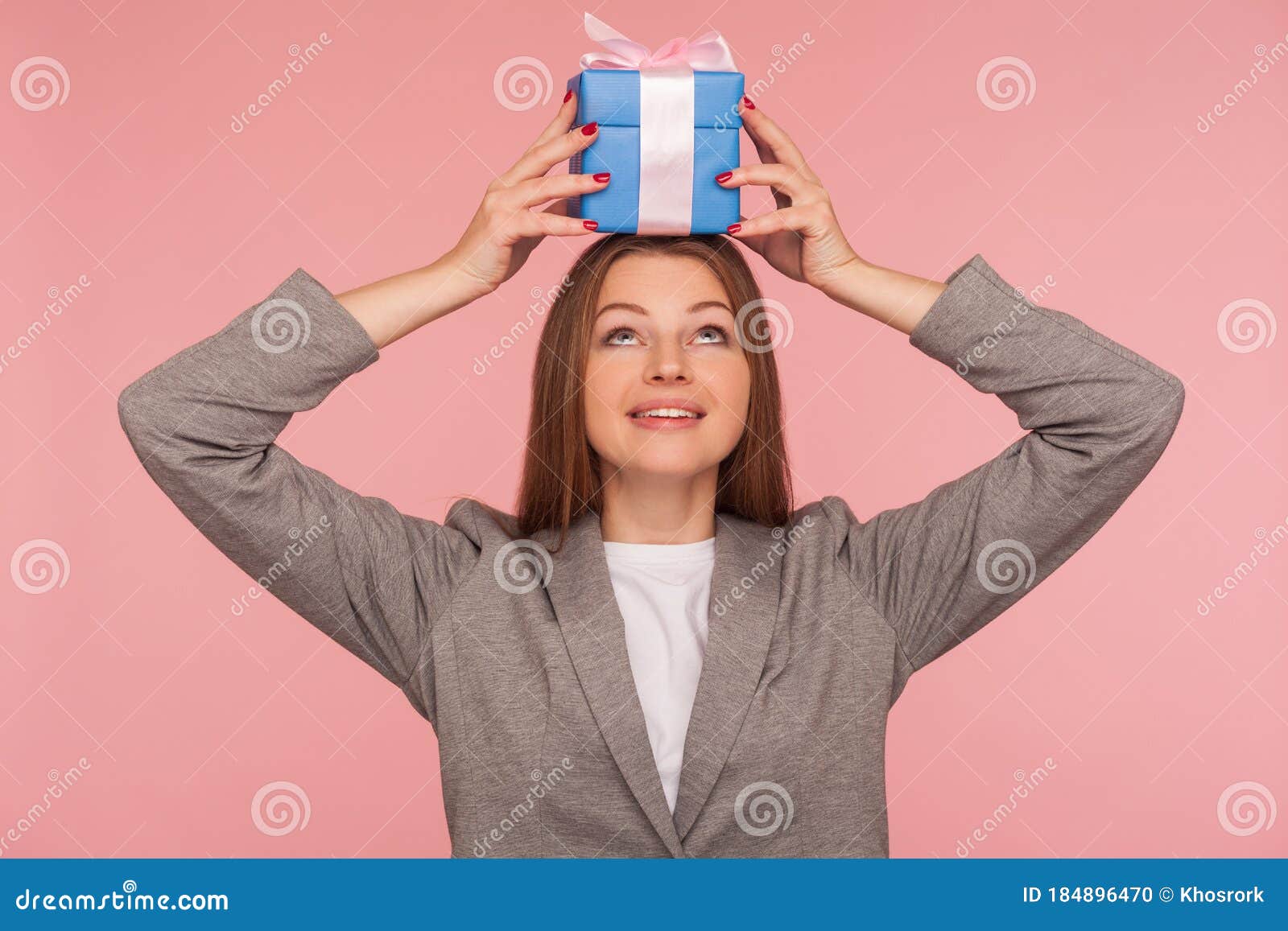 portrait of funny joyful businesswoman in suit jacket holding present on head and smiling, celebrating anniversary