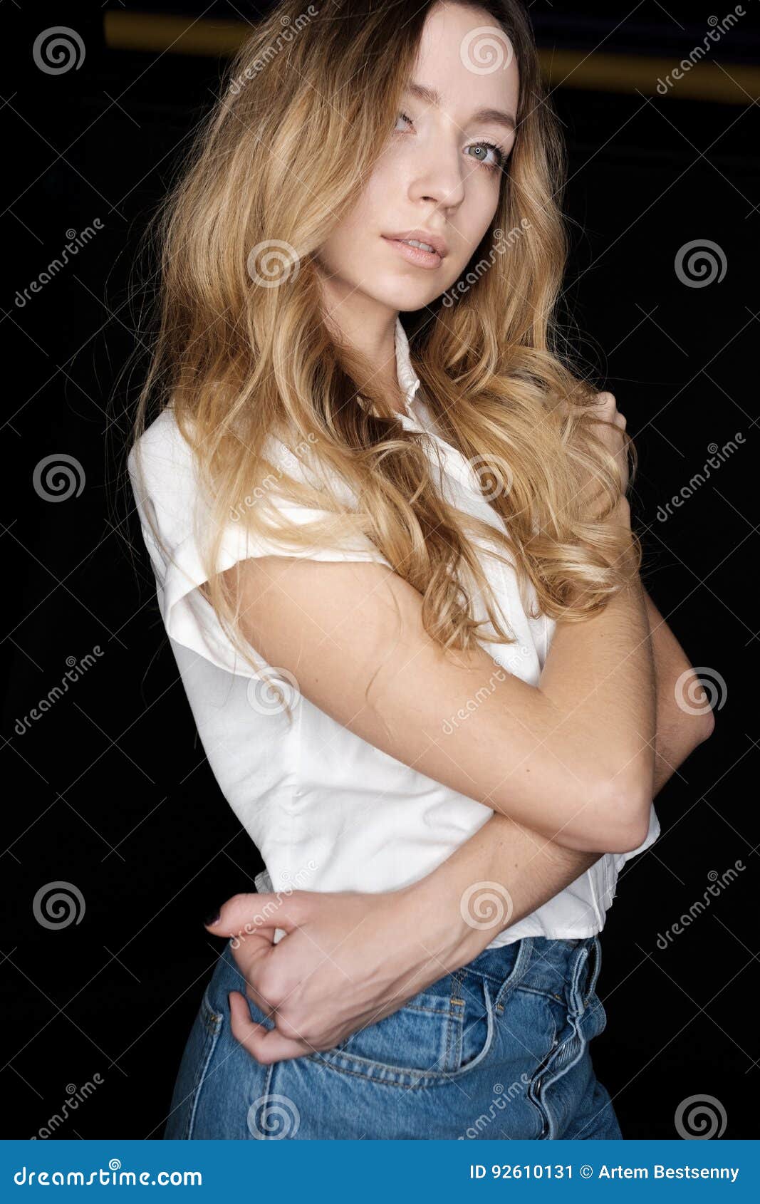 Portrait of Girl of Blonde in a White Shirt and Jeans Against a Dark ...