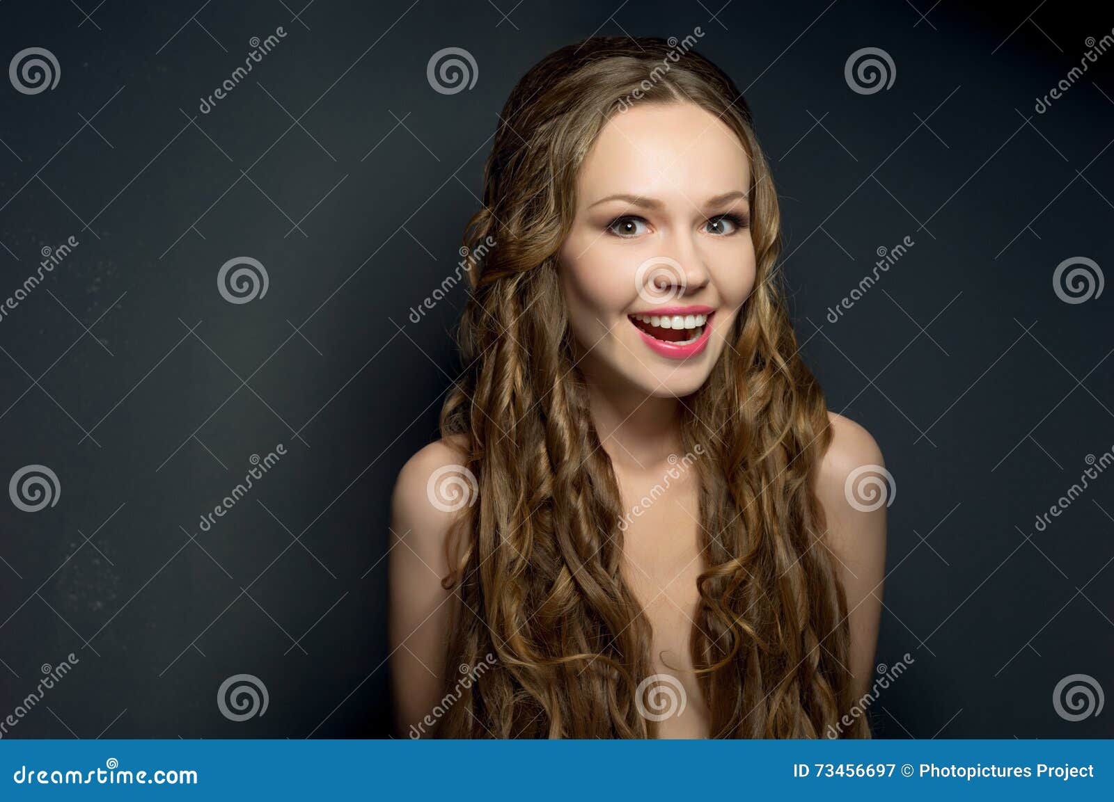 portrait of a glad beautiful young woman on dark background.