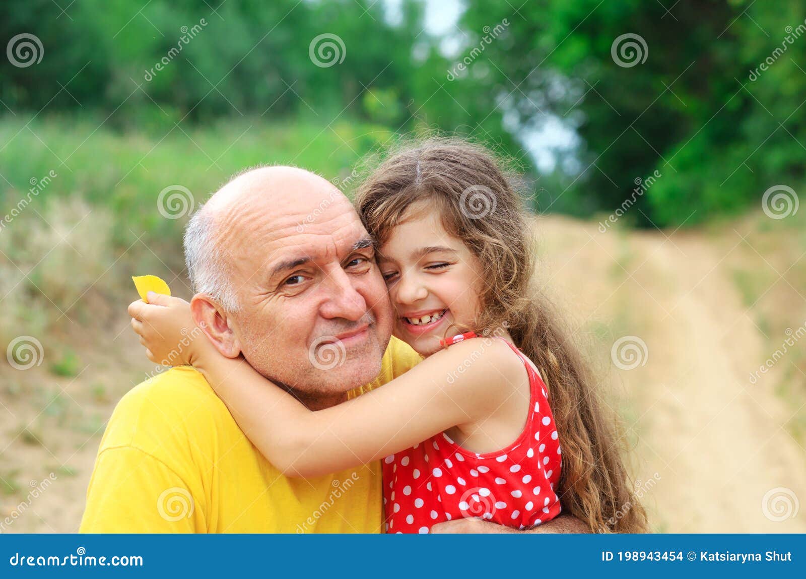 portrait of granddad and granddaughter smiling at the park