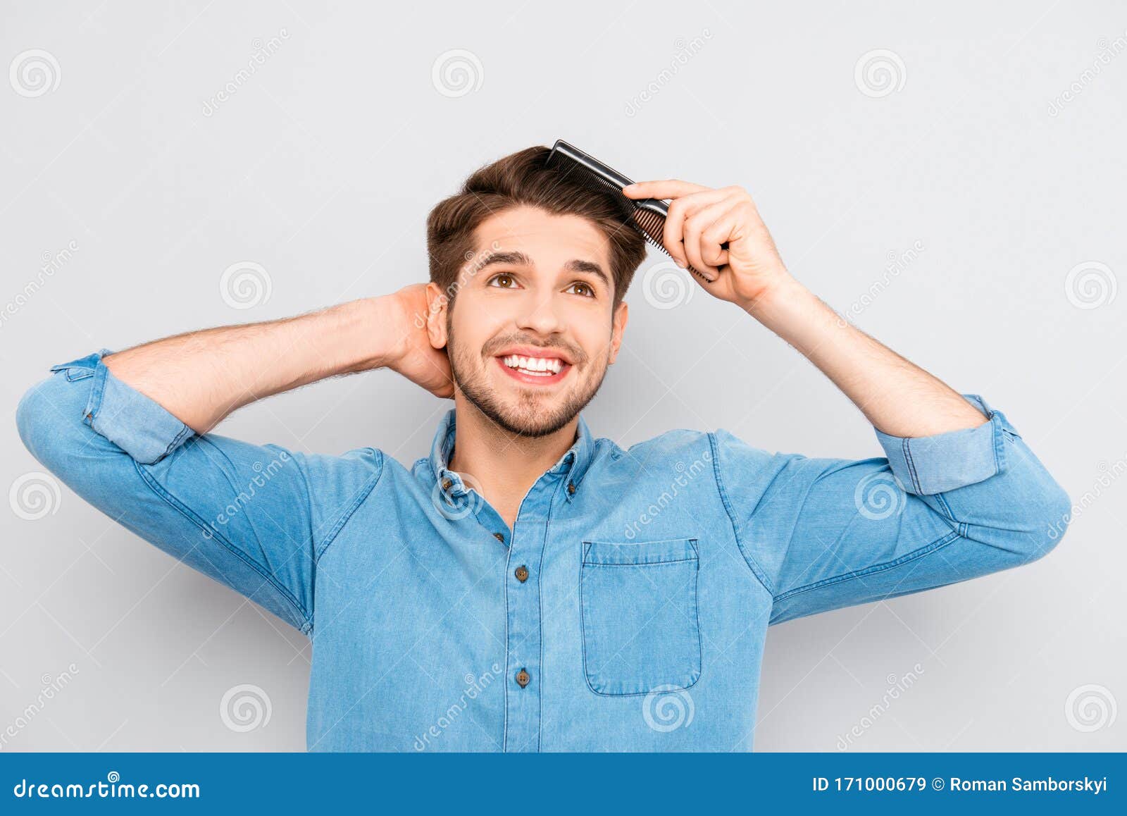 portrait of handsome cheerful young man combing his hair
