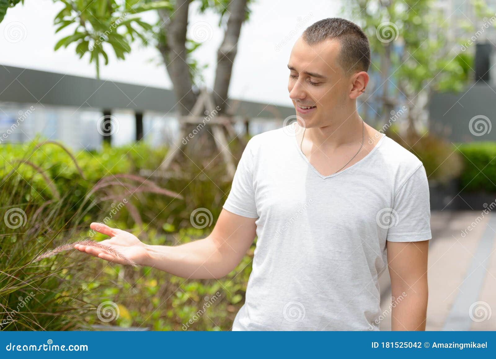 portrait of happy handsome man touching grass in the park