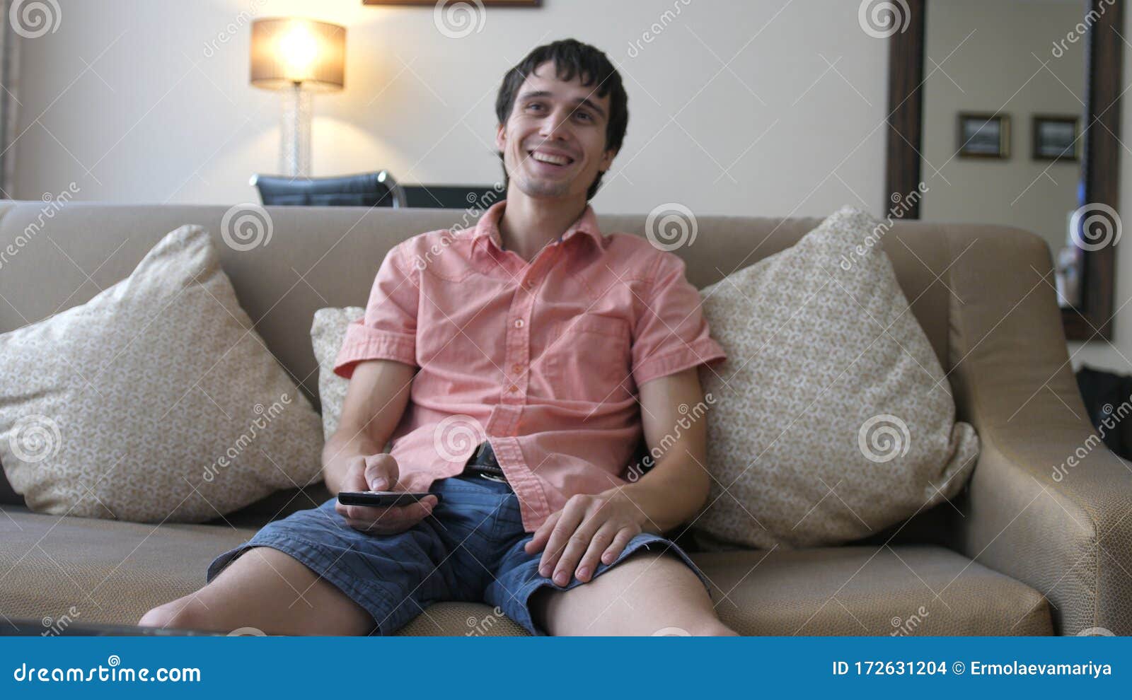 Portrait of a Handsome Man Sitting on a sofa at Home Watching Comedy Series on TV.