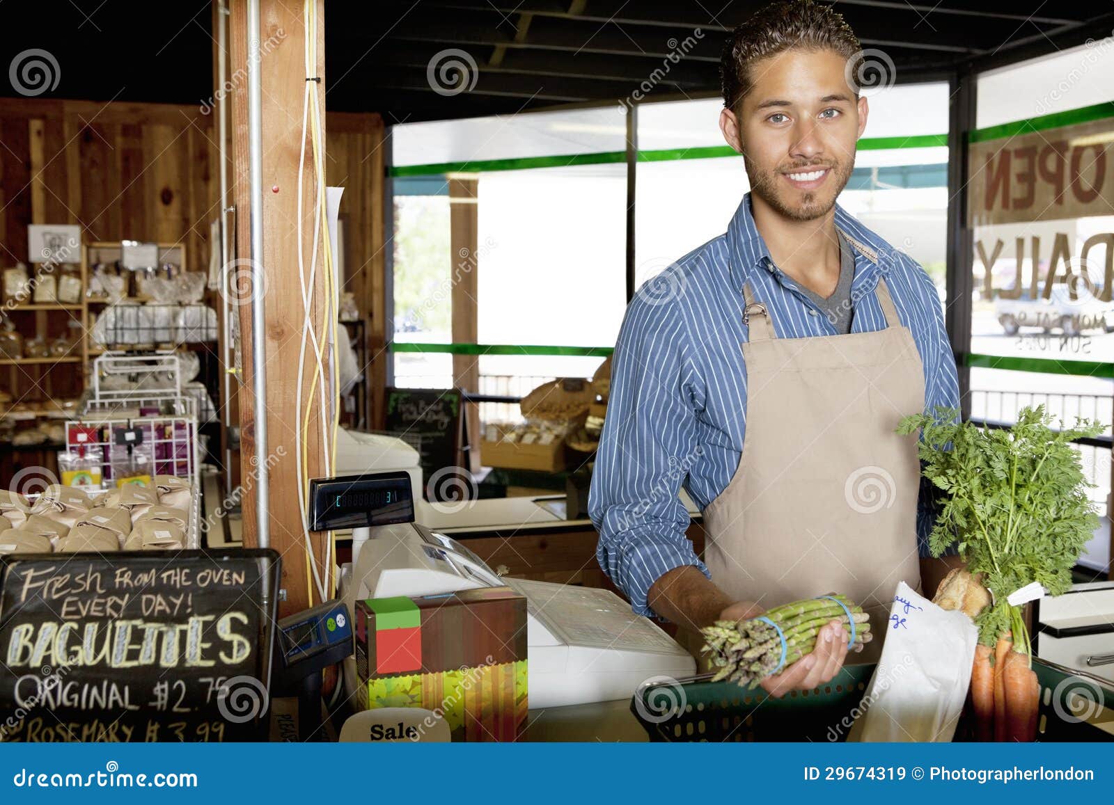 portrait of handsome young store clerk holding vegetable in supermarket