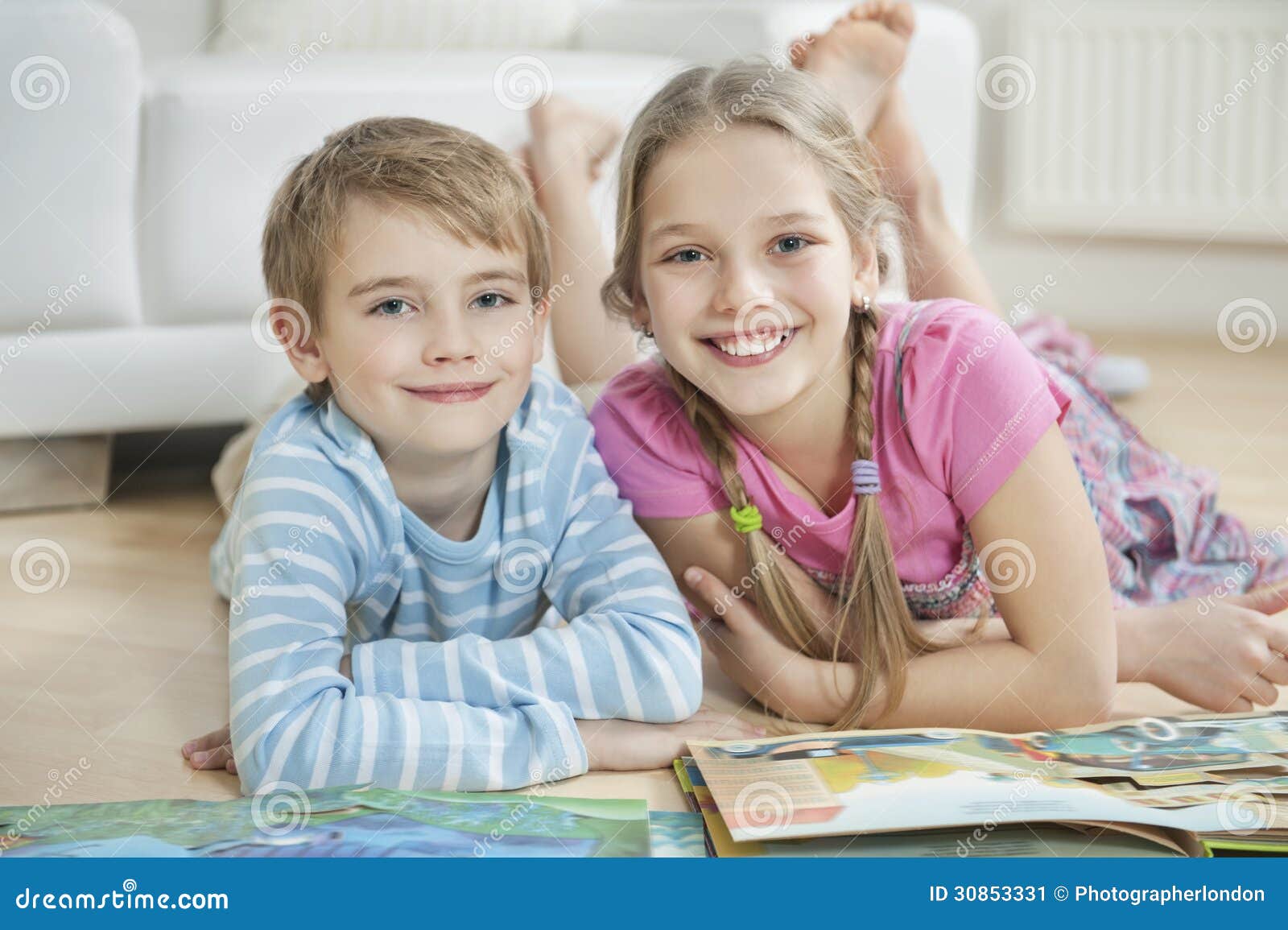 portrait of happy brother and sister with story books while lying on floor