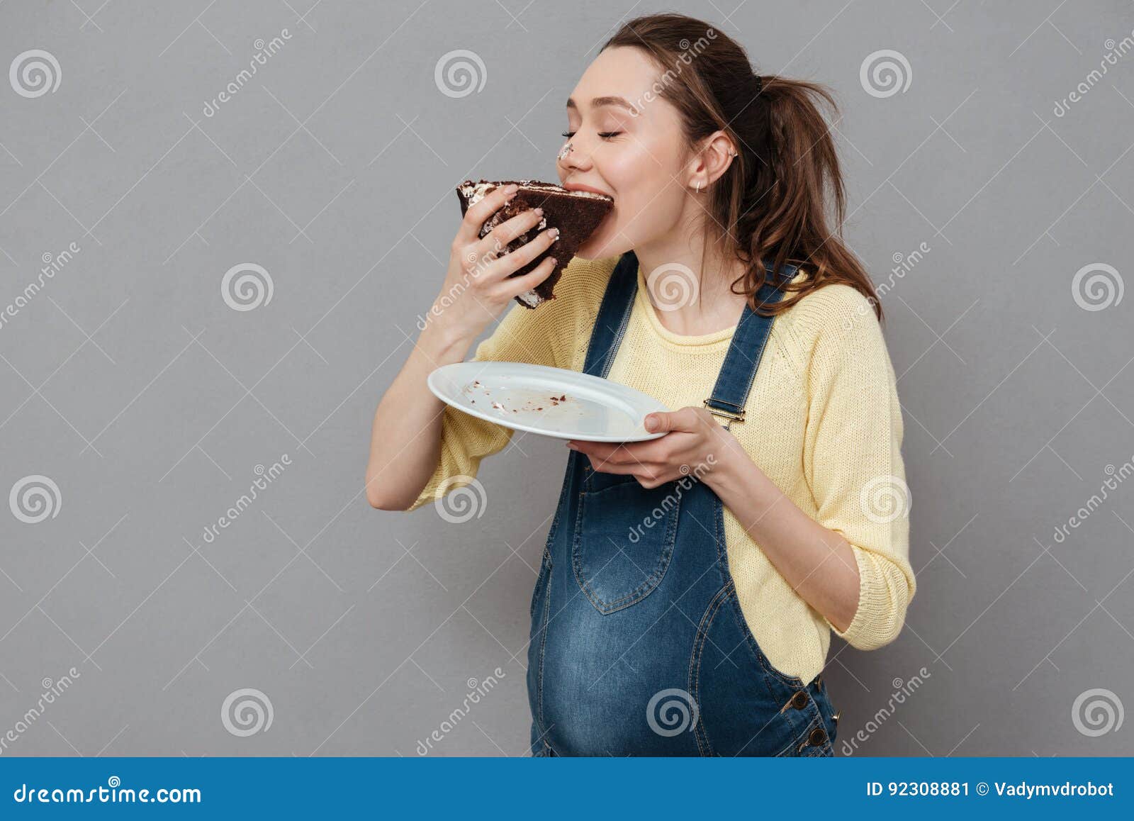 Portrait Of A Happy Cute Pregnant Woman Biting Chocolate