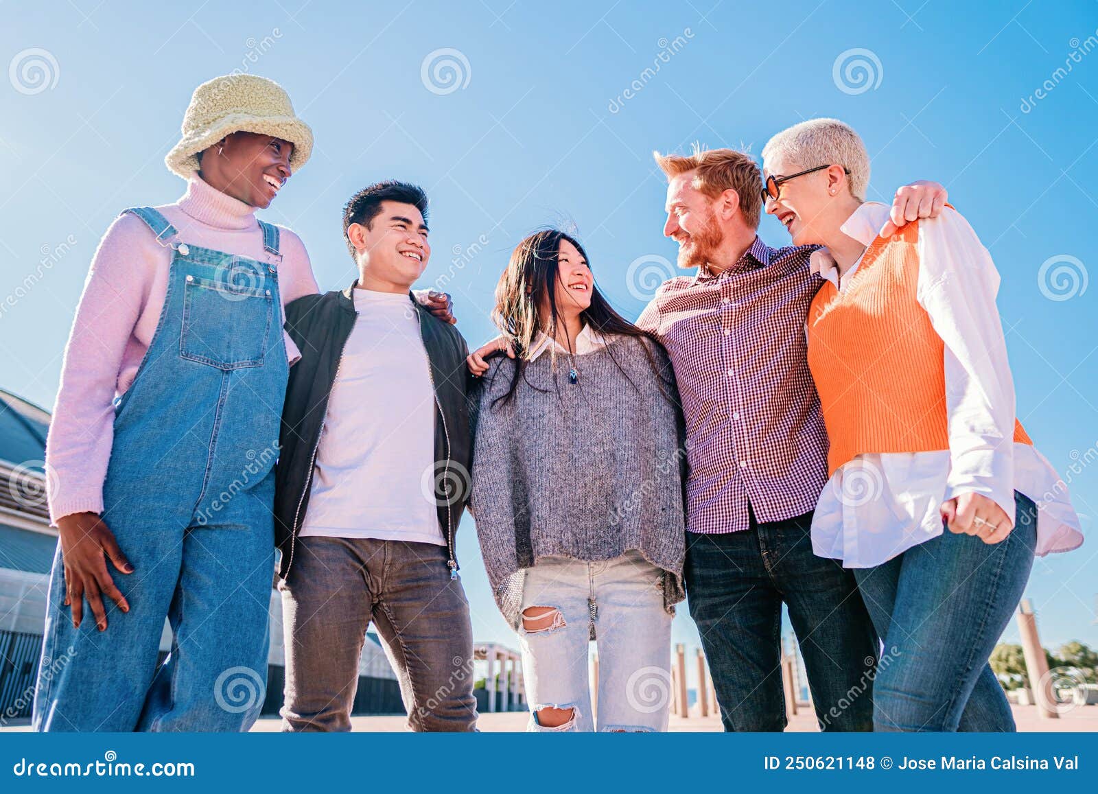 portrait of happy friends standing with arms around each other's shoulders. group of multiracial friends having fun