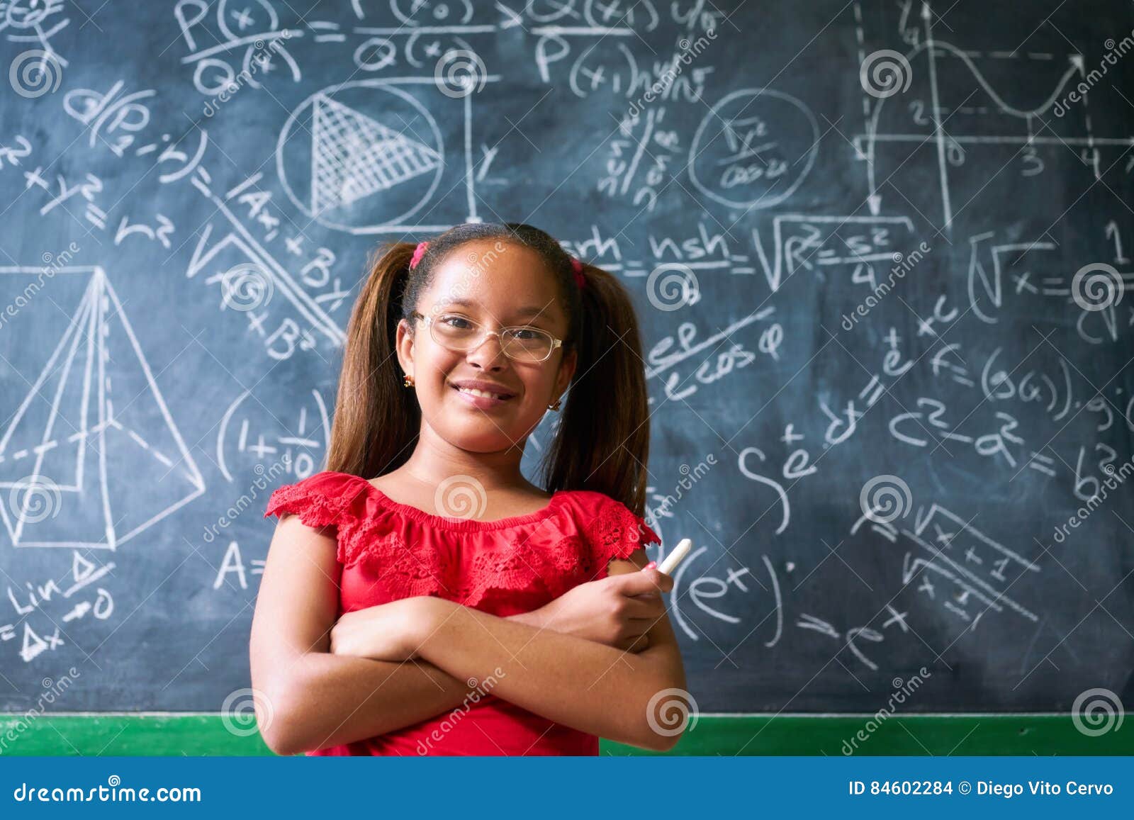 portrait happy girl resolving complex math problem on blackboard