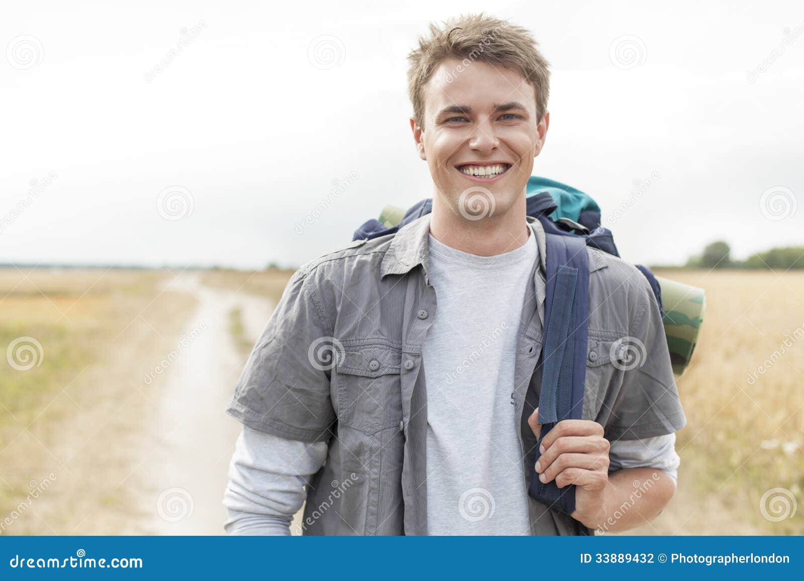 portrait of happy male hiker with backpack standing on field