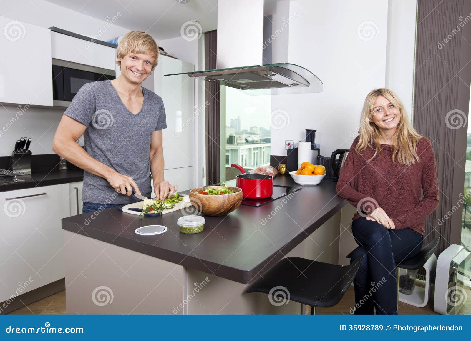 Portrait Of Happy Man Cutting Vegetables While Woman Sitting At