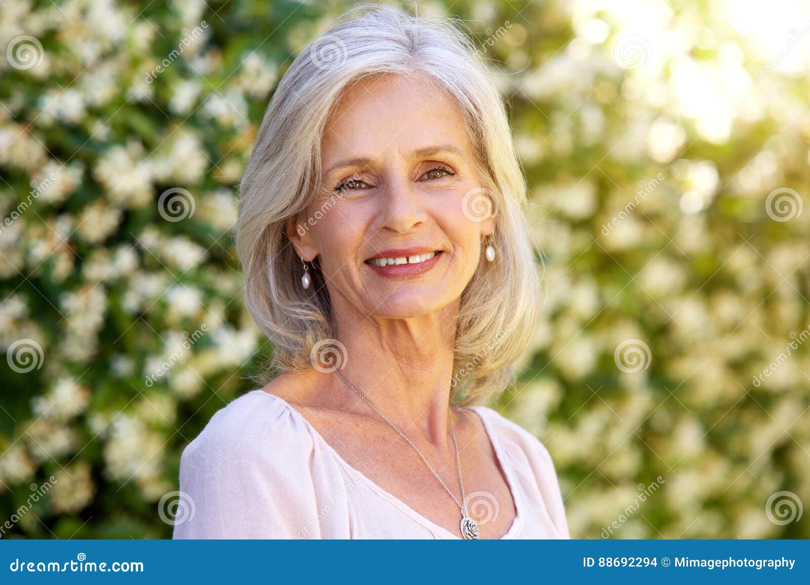 portrait of happy older woman standing outside in summer